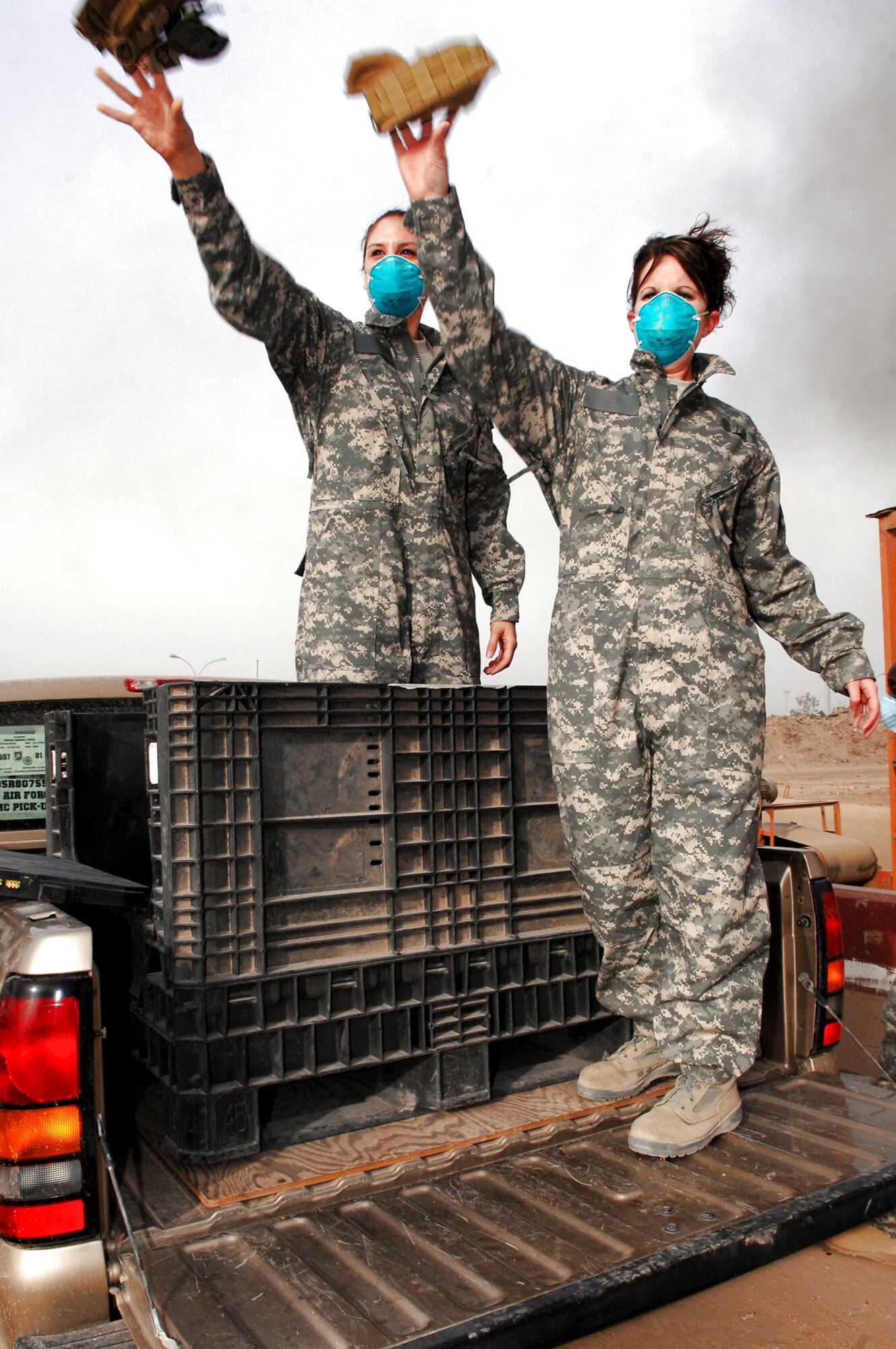 Senior Airman Frances Gavalis and Staff Sgt. Candice Zalewski toss unserviceable uniform items into a burn pit March 10 at Balad Air Base, Iraq. Burning uniform items is done to ensure opposing forces do not obtain them. Airman Gavalis is deployed from Kirtland Air Force Base, N.M., and Sergeant Zalewski is deployed from Luke AFB, Ariz. Both are 332nd Expeditionary Logistics Readiness Squadron equipment managers. (U.S. Air Force photo/Senior Airman Julianne Showalter) 
