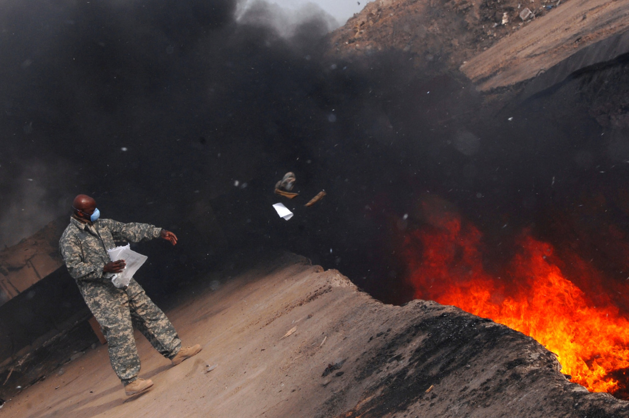 Master Sgt. Darryl Sterling tosses unserviceable uniform items into a burn pit March 10 at Balad Air Base, Iraq. The 332nd Expeditionary Logistics Readiness Squadron has a central collection point that can be used by servicemembers and Department of Defense civilians for unserviceable uniform items that need to be burned. Sergeant Sterling, a 332nd ELRS equipment manager, is deployed from Luke Air Force Base, Ariz. (U.S. Air Force photo/Senior Airman Julianne Showalter) 
