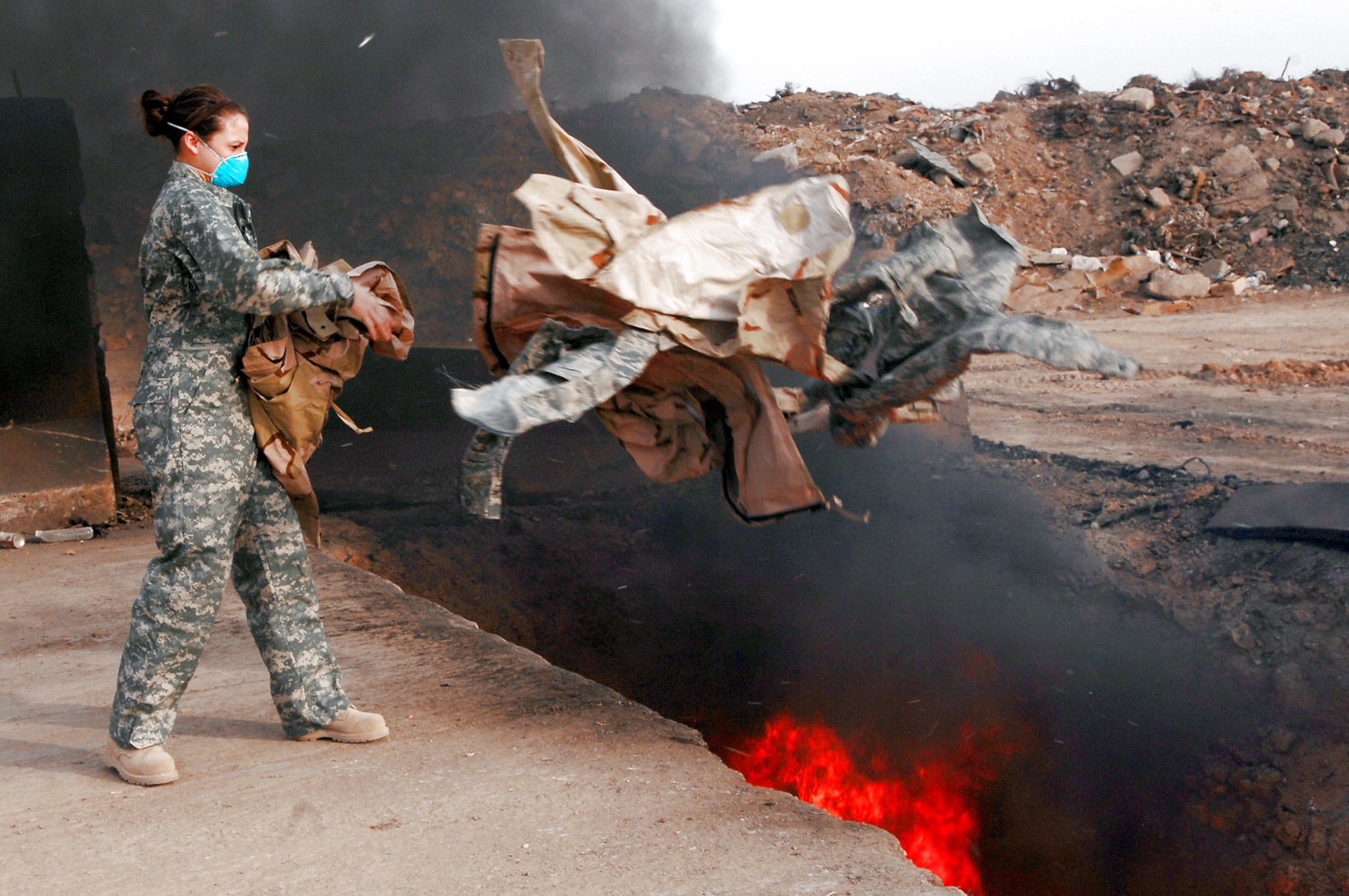 Senior Airman Frances Gavalis tosses unserviceable uniform items into a burn pit March 10 at Balad Air Base, Iraq. Military uniform items turned in must be burned to ensure they cannot be used by opposing forces. Airman Gavalis, a 332nd Expeditionary Logistics Readiness Squadron equipment manager, is deployed from Kirtland Air Force Base, N.M. (U.S. Air Force photo/Senior Airman Julianne Showalter) 
