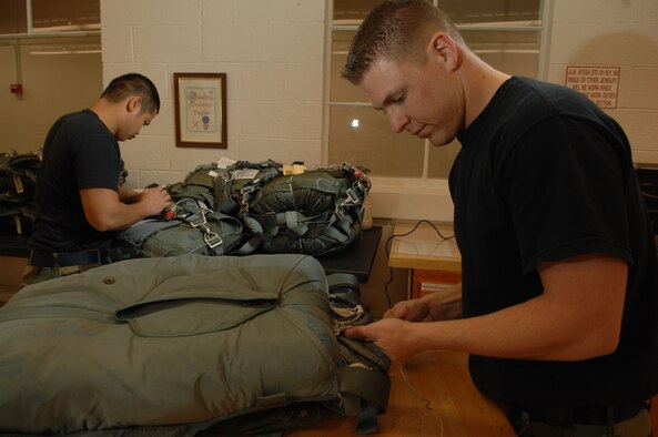 Staff Sgt. Derek Gilbert, 355th Operations Supprt Squadron, parachute shop replaces the ripcord housing tacking of a BA-18M parachute assembly as Airman 1st Class Justin Petros completes the final visual inspection of the parachutes before going through the final quality check.