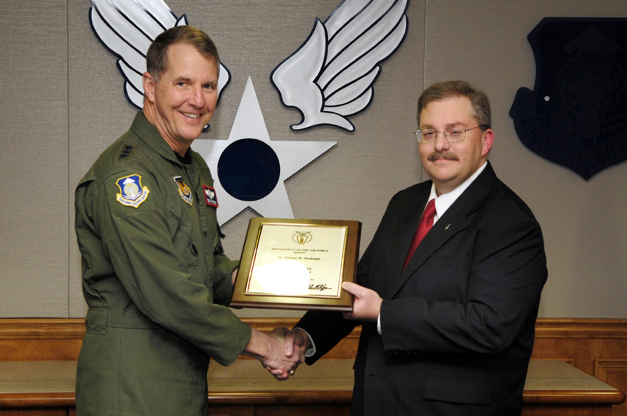 ESC Commander Lt. Gen. Ted Bowlds presents the Senior Level certificate to Dr. Tim Rudolph March 7 in a first-of-its-kind ceremony at Hanscom.  Dr. Rudolph, who is now serving as technical advisor for system of systems networking and interoperability within the 653rd Electronic Systems Wing, has become the first Senior Level employee in the center’s history. (U.S. Air Force photo by Mark Wyatt.)