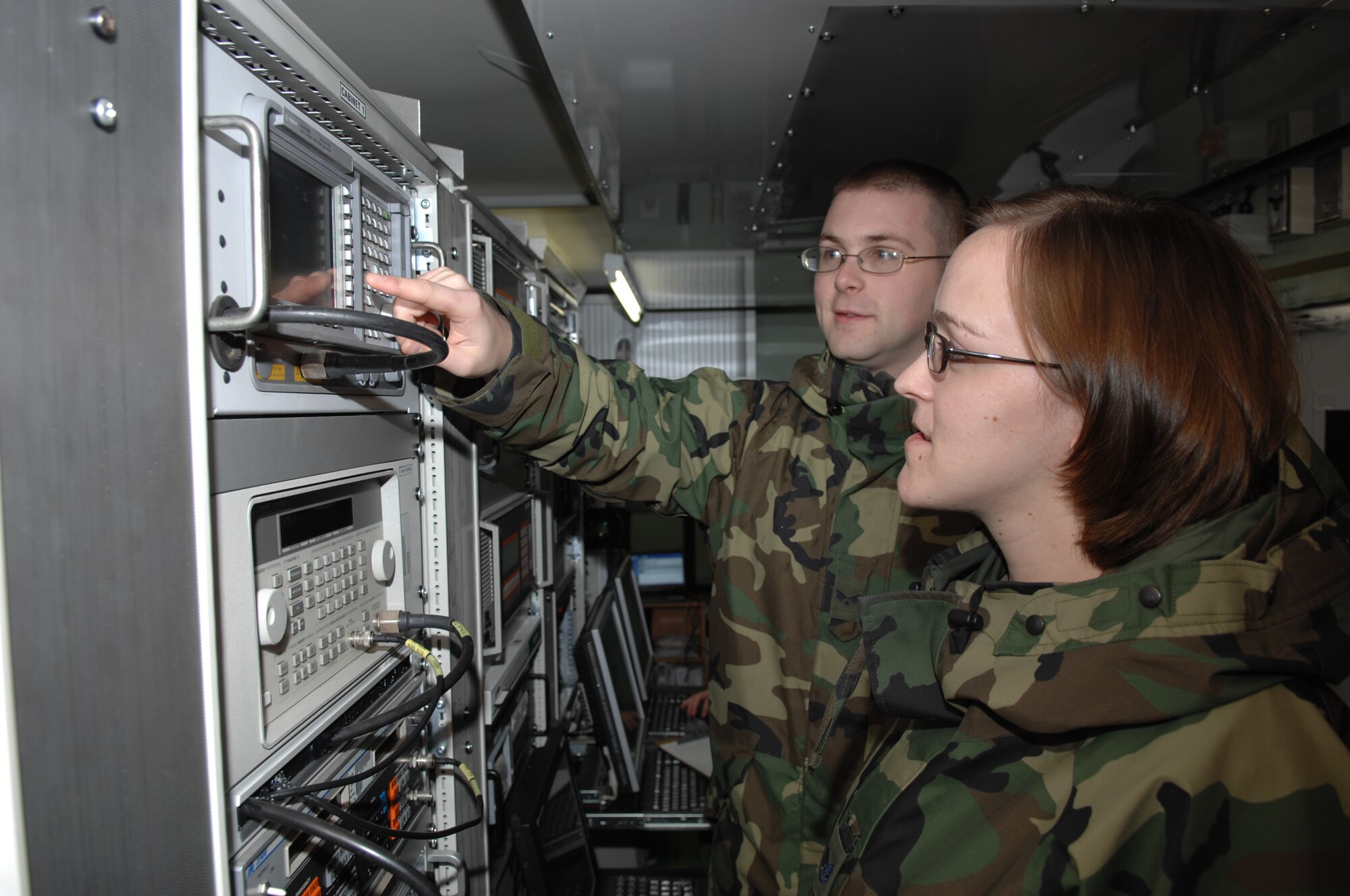 Senior Airman Adam Walters, commercial satellite imagery geospatial analyst, and Staff Sgt. Susanne Dehne, an imagery collection analyst, program the setting on a Spectrum Analyzer.  The analyzer measures the strength of the signal received by the Eagle Vision-1 antenna from commercial satellites.  (U.S. Air Force photo by Senior Master Sgt. Hollis Dawson)
