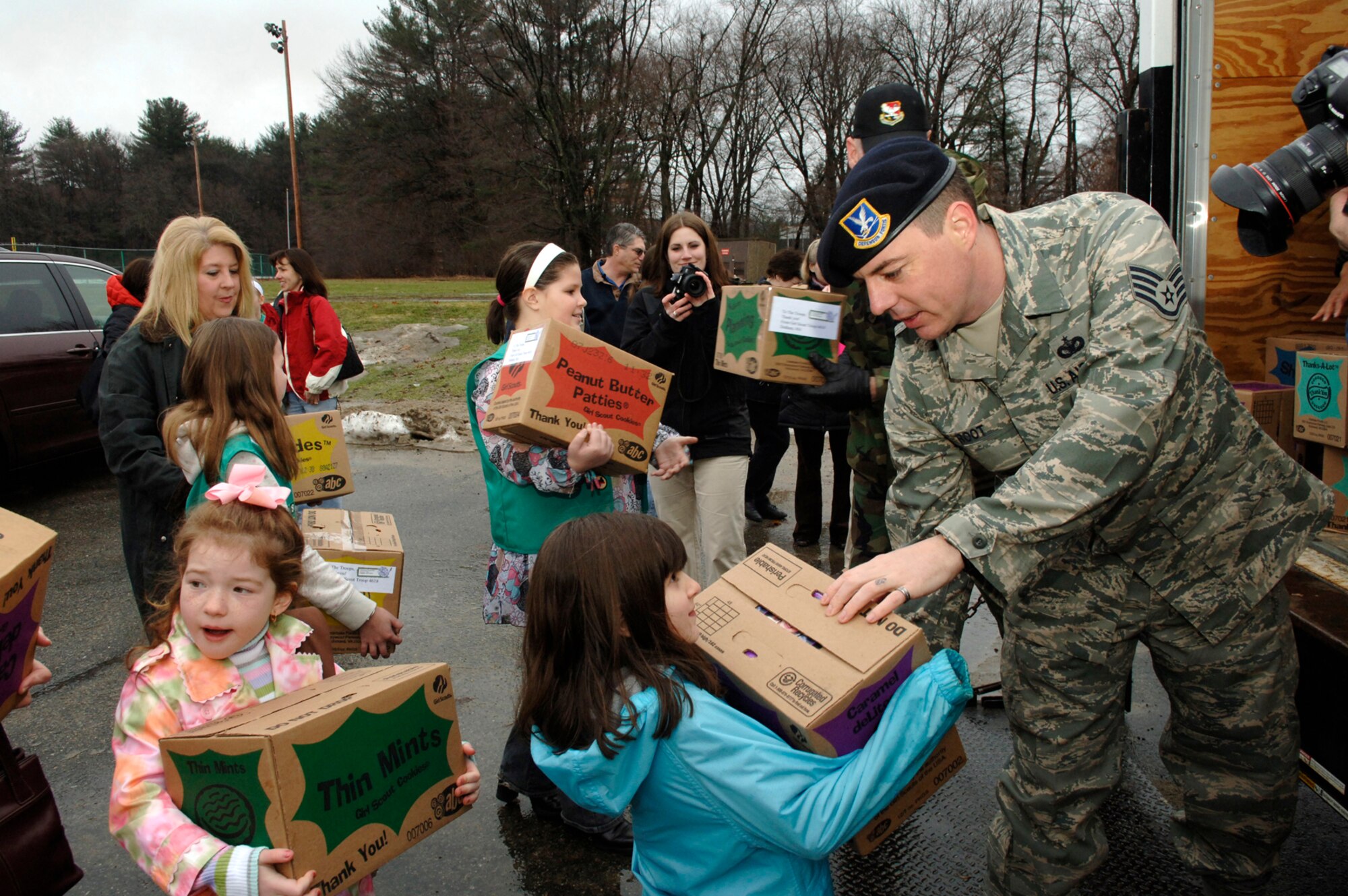 HANSCOM AFB, Mass. – Staff Sgt. Terrance Root (right), 66th Security Forces Squadron, lends a helping hand to some of the 400 Girl Scouts from across Eastern Massachusetts that came to the base March 8 to deliver more than 10,000 boxes of Girl Scout cookies. The cookies were donated by the Girl Scouts to Hanscom’s Company Grade Officer Troop Care Package drive. The cookies will be sent to deployed military personnel around the world. The girls and Airmen worked side by side to unload the cookies and after, Col. Tom Schluckebier, 66th Air Base Wing commander thanked the girls for their efforts. (U.S. Air Force photo by Walter Santos)

