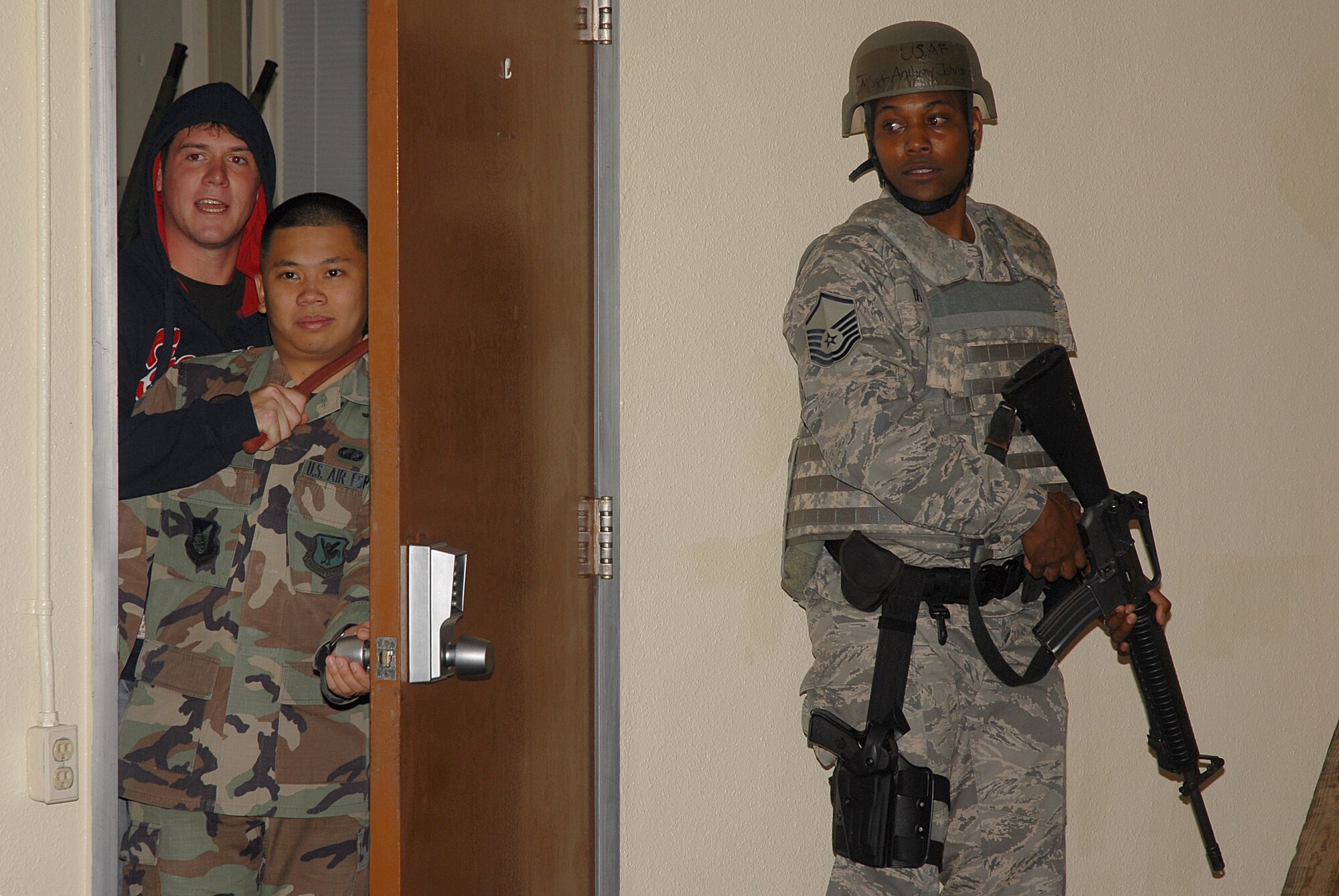 Master Sgt. Anthony Johnson, 18th Security Forces Squadron, hides behind the door as the perpetrator of a hostile situation scenario at the 18th Comptroller Squadron building comes out to show his intentions if his demands are not met, during the 2008 Pacific Air Forces Operational Readiness Inspection at Kadena Air Base, Japan, March 11, 2008. PACAF is conducting the inspection from March 9 to 15 to validate the mission readiness of the 18th Wing. (U.S. Air Force photo/Staff Sgt. Chrissy FitzGerald) 