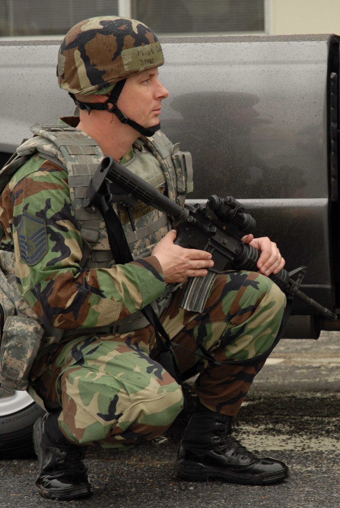 Master Sgt. Keith Collins, 18th Security Forces Squadron, takes shelter behind a vehicle during a hostile situation scenario at the comptroller squadron building, during the 2008 Pacific Air Forces Operational Readiness Inspection at Kadena Air Base, Japan, March 11, 2008. PACAF is conducting the inspection from March 9 to 15 to validate the mission readiness of the 18th Wing. (U.S. Air Force photo/Staff Sgt. Chrissy FitzGerald)