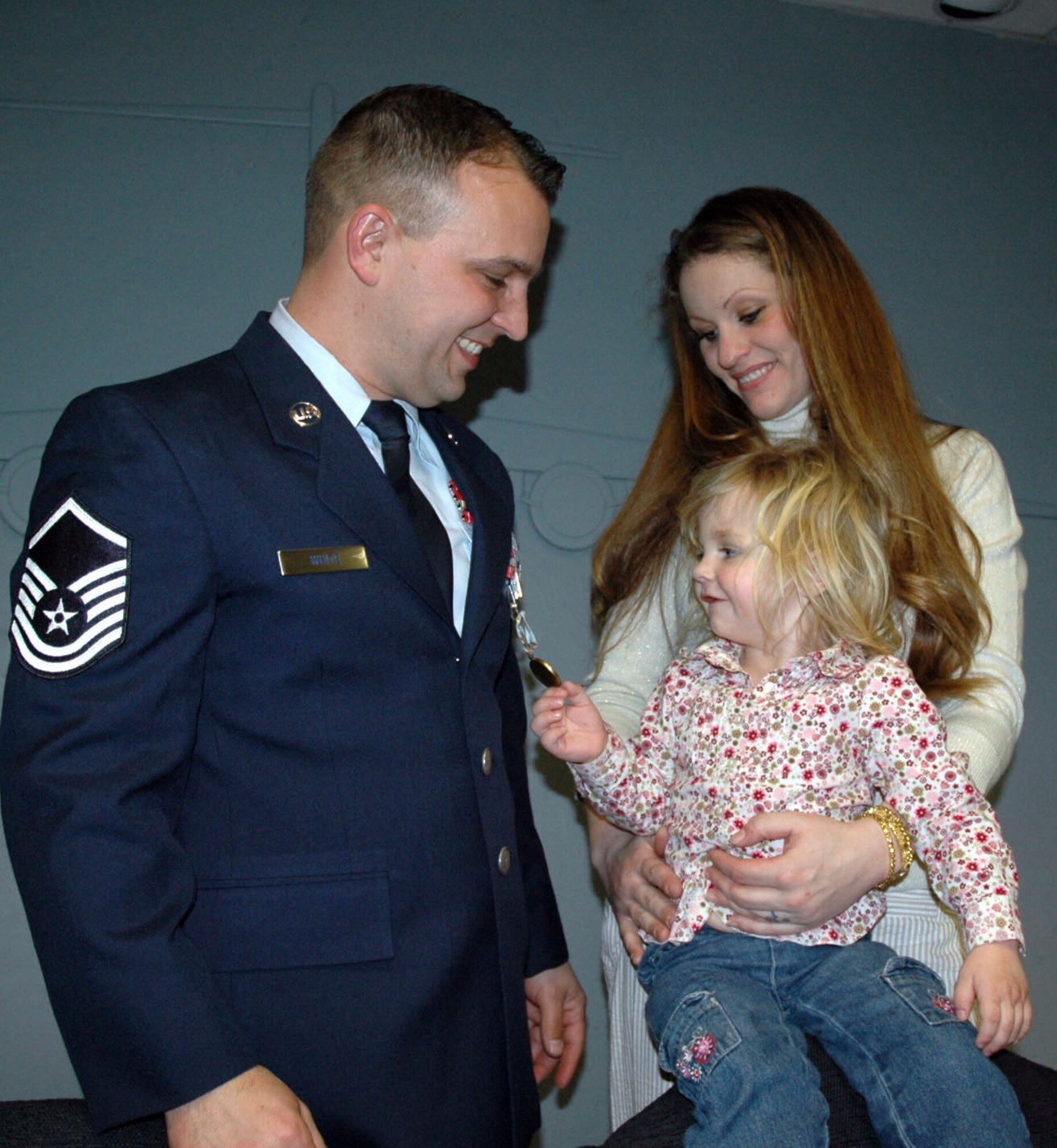 Emily Norman, held by her mother Ericka Larsen, plays with the Air Force Airman's Medal awarded to Master Sgt. Phillip White, 446th Aircraft Maintenance Squadron. Sergeant White, a Reservist, was presented the medal March 9 at McChord Air Force Base, Wash., for heroic actions.  In July 2006, Sergeant White saved Emily and her sister Allison from a burning car following an auto accident on state Route 101. (U.S. Air Force photo/ Capt. Sabra Brown)