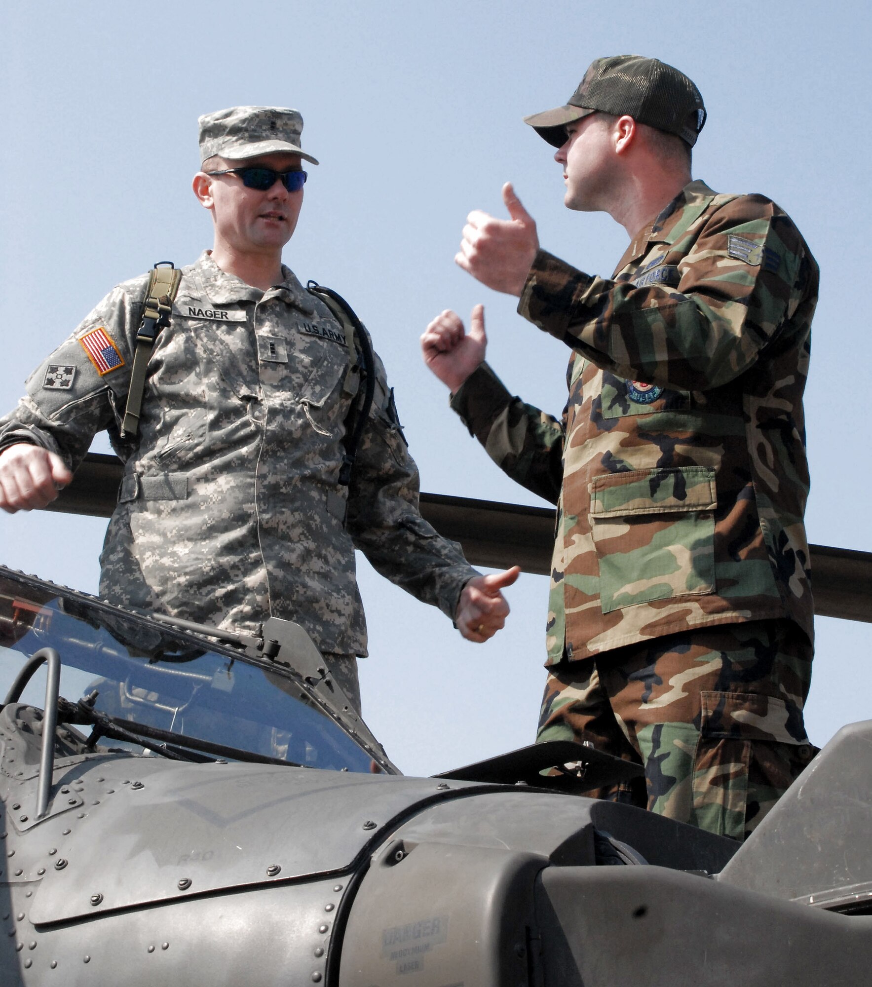 While standing atop an AH64D Apache helicopter, Chief Warrant Officer 3rd Class Pat Nager, a standardization instructor pilot with Charlie Company, 42nd Aviation Battalion from Camp Humphreys, South Korea, answers a question about fire rescue operations from Senior Airman Joshua McGinnis, a firefighter with the 8th Civil Engineer Squadron at Kunsan Air Base, South Korea. Army aviators brought the helicopter to Kunsan March 10 to inform Airmen about the aircraft and the Army's current mission in South Korea.  (U.S. Air Force photo/Staff Sgt. Darcie Ibidapo)