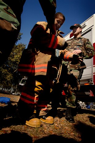 Lamar Sterling, fifth-grader from Midland Park Elementary School, puts on the fire protection uniform with help from Airmen from the 437th Civil Engineer Squadron fire department during the Earth Day celebration on base Wednesday. (U.S. Air Force photo/Senior Airman Nicholas Pilch)