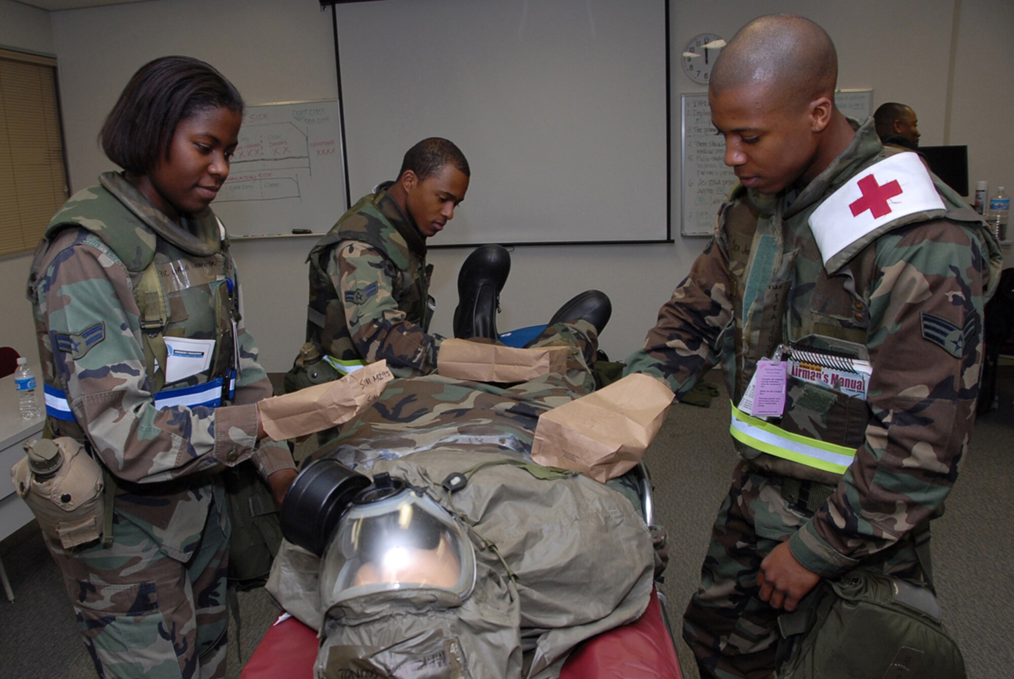 Airman 1st Class Gala Hamilton, Airman 1st Class Richard Glass, and Senior Airman Justin Rice, all from the 18th Dental Squadron, use an M291/295 decontamination kit to pat a contaminated victim during the 2008 Pacific Air Forces Operational Readiness Inspection at Kadena Air Base, Japan, March 11, 2008. PACAF is conducting the inspection from March 9 to 15 to validate the mission readiness of the 18th Wing. (U.S. Air Force photo/Staff Sgt. Darnell T. Cannady)
