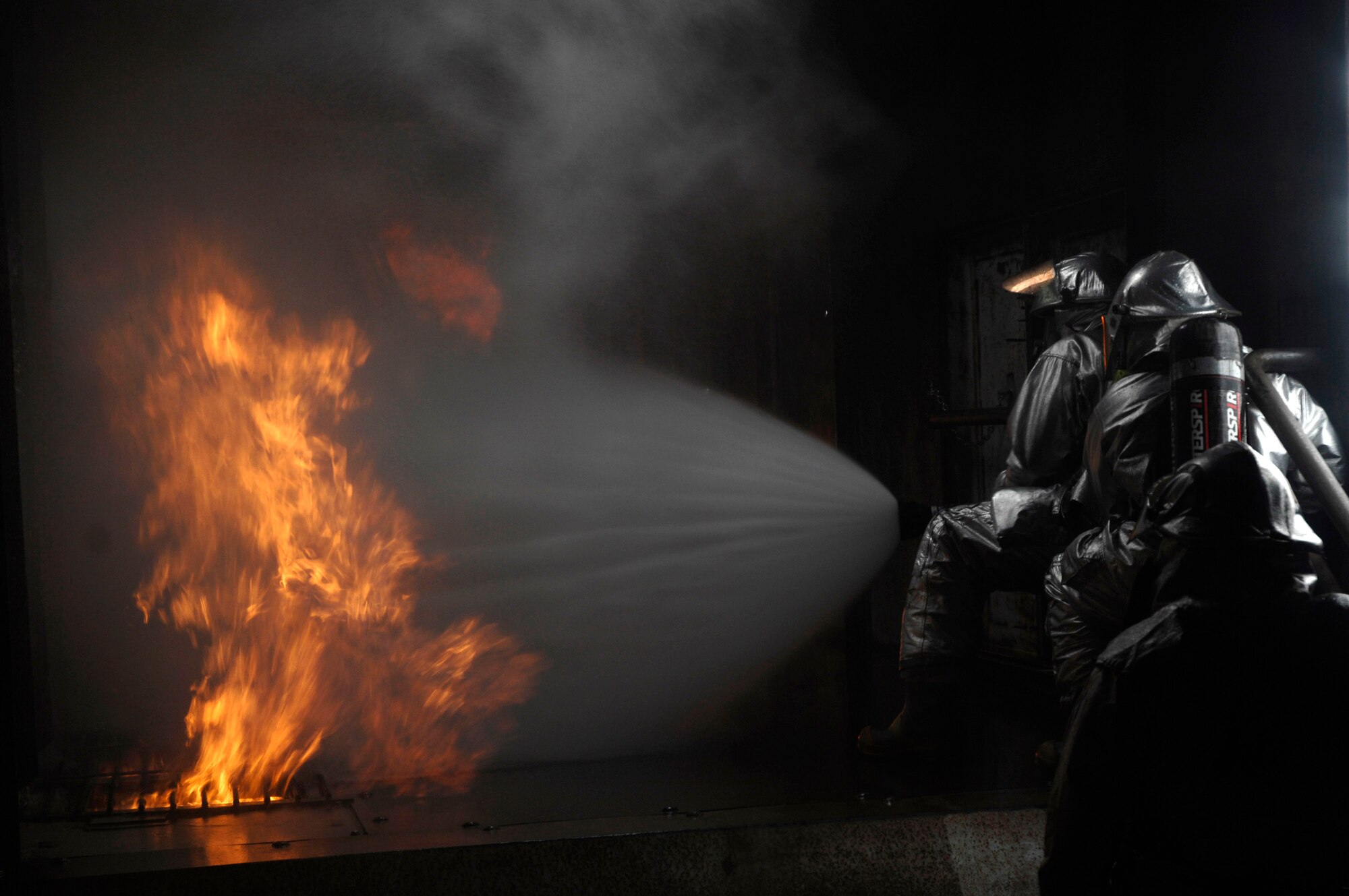 48th Civil Engineer Squadron firefighters extinguish a simulated battery fire inside an aircraft fire trainer March 8 at Royal Air Force Mildenhall, England. Firefighters must train constantly to stay proficient in their aircraft rescue and firefighting skills. (U.S. Air Force photo/Airman Perry Aston) 
