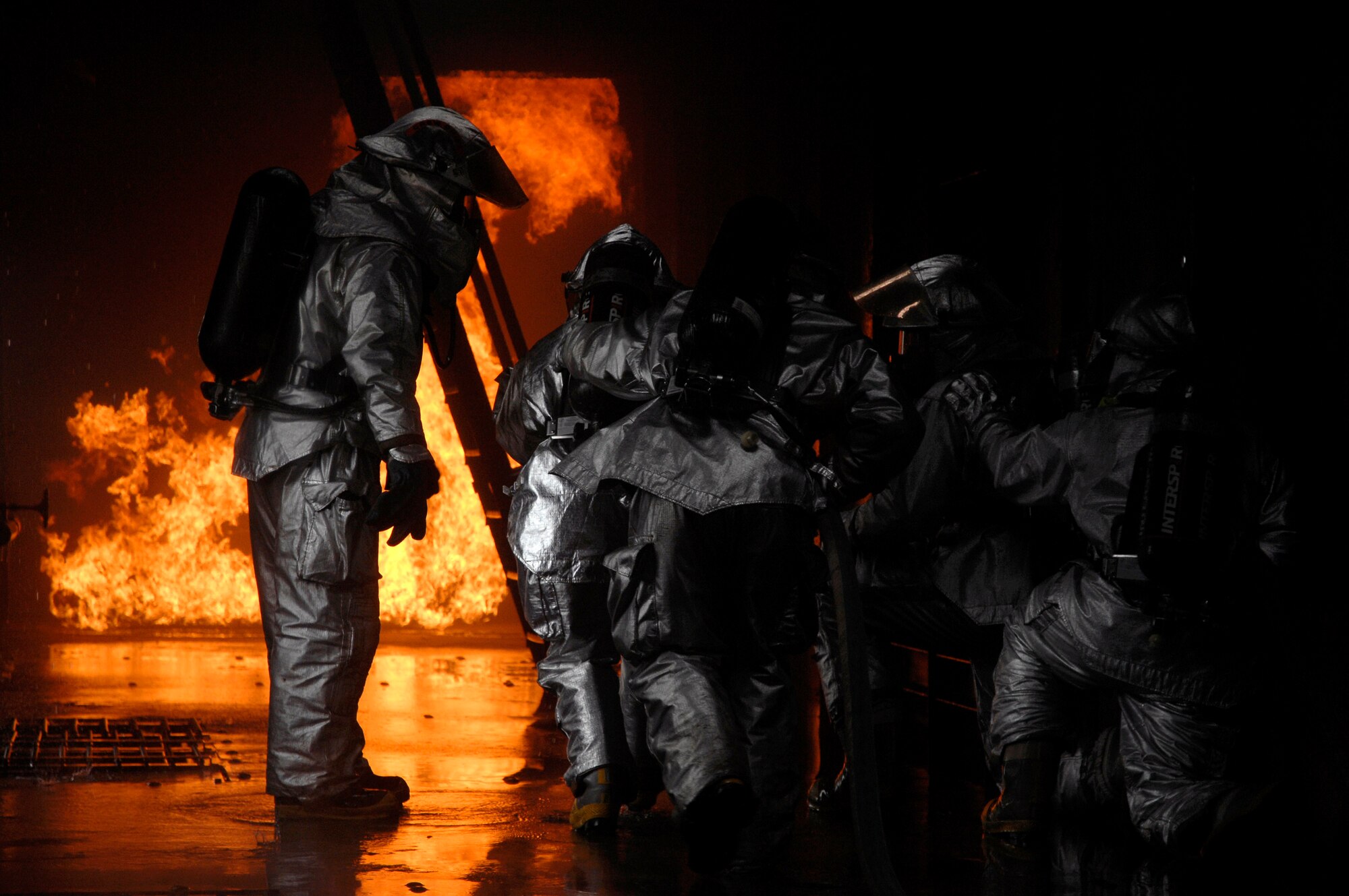 Master Sgt. Walter Wright (left) instructs firefighters to advance toward the simulated cargo fire March 8 at Royal Air Force Mildenhall, England. Sergeant Wright, a 48th Civil Engineer Squadron firefighter, was the training instructor for all internal fires inside the aircraft fire trainer. (U.S. Air Force photo/Airman Perry Aston) 
