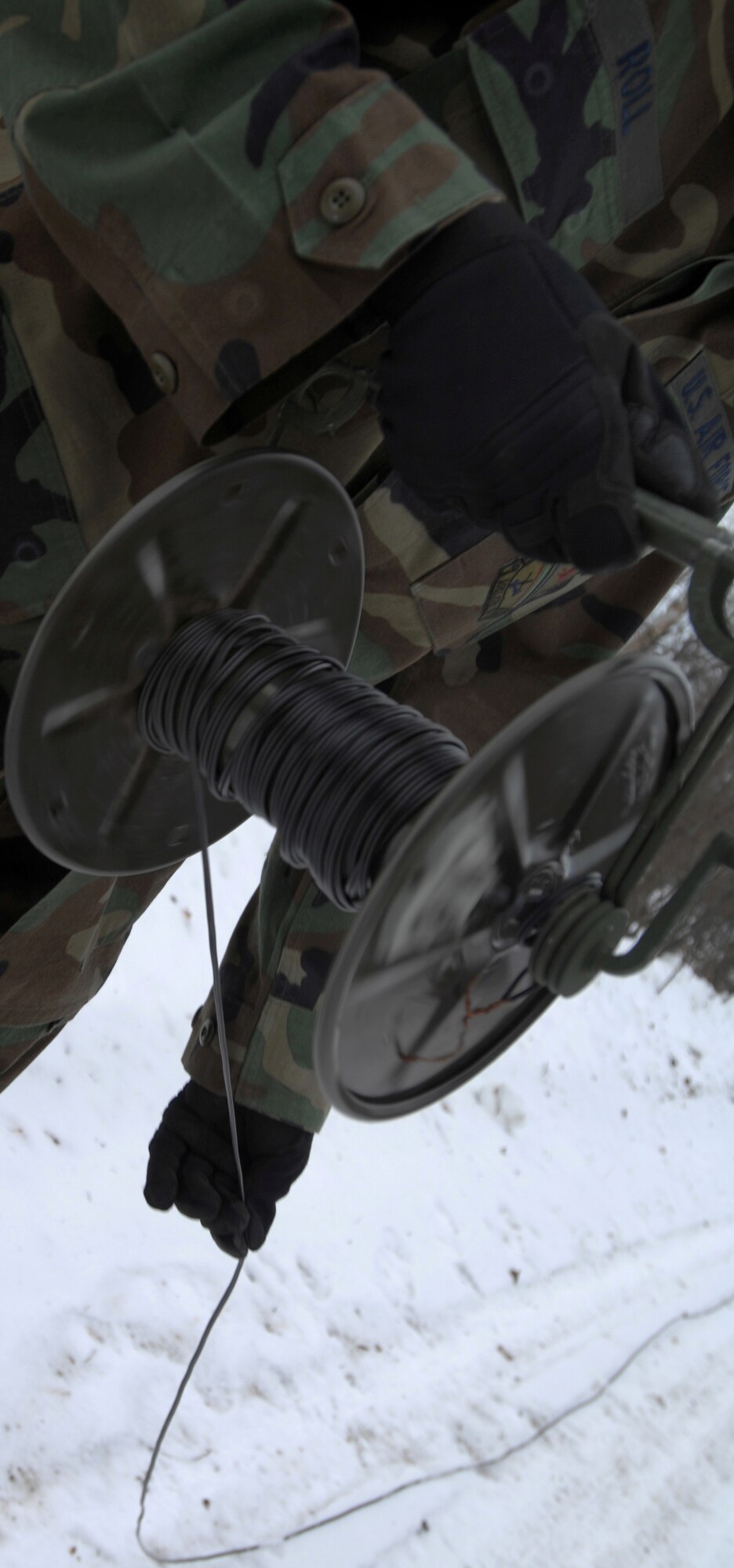 Airman 1st Class Dallas Roll unwinds firing wire in preparation for a controlled explosion March 4, 2008 at Eielson Air Force Base, Alaska. The wire connects the firing mechanism to the explosive charges for detonation from a safe distance. (U.S Air Force photo by Staff Sgt. Eric T. Sheler)