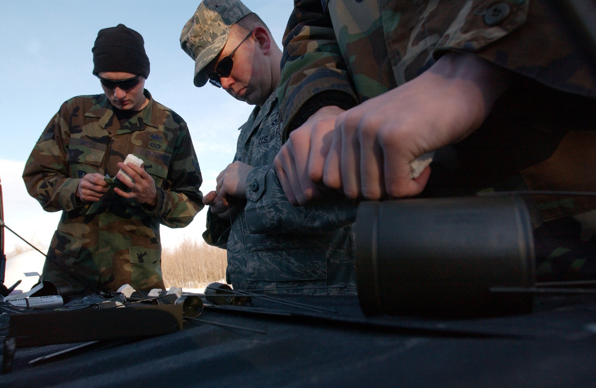 (From left to right) Explosive ordnance apprentices Airmen 1st Class Dallas Roll,  Matthew Leatherman and Nikolas Cox place plastic explosive C4 into shape charge containers prior to explosive ordnance training Feb. 21, 2008 at Eielson Air Force Base, Alaska. The charge containers hold the shape of the C4, which determines the direction of an explosion. (U.S Air Force photo by Staff Sgt. Eric T. Sheler)