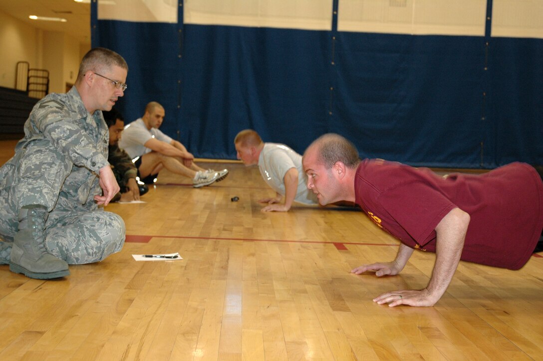 BUCKLEY AIR FORCE BASE, Colo. -- John Dougherty (left), 460th Mission Support Squadron superintendent, encourages Michael Mariner, 2nd Space Warning Squadron, to complete as many push-ups as he can in 10 minutes during the Chief's Push-Up Challenge here March 11. (U.S. Air Force photo by Staff Sgt. Sanjay Allen)