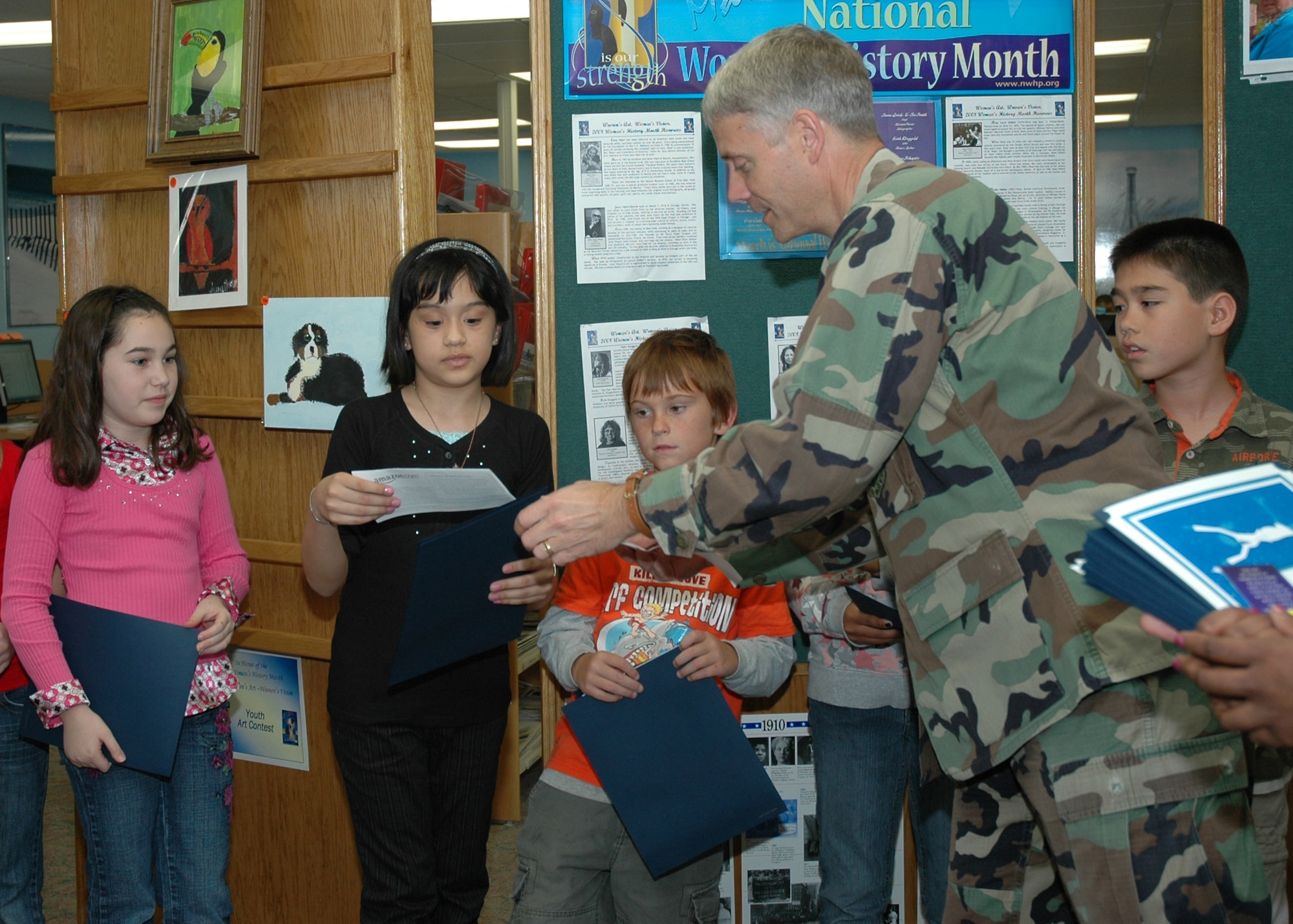 EGLIN AIR FORCE BASE, Fla. -- Col. Eric Pohland, 96th Air Base Wing commander, presents a gift certificate to  Gabrielle Caggiano, the winner of the age 8 to 12 category of the Eglin Youth Art Contest at the base library March 11. The contest was sponsored by the Women's History Month Committee because it related to the theme of the month, "Women's Art - Women's Vision." Out of 48 entries, three winners were chosen from three age categories. Joe Blankenberger was chosen in the age 7 and under category and Amber Kaderbeck was chosen in the age 13 to 17 category. All of the children who entered the contest recieved a certificate from the Women's History Month Committee. (U.S. Air Force photo by Staff Sgt. LuCelia Ball)