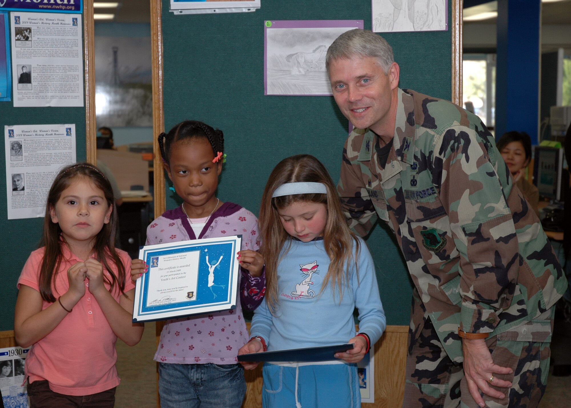 EGLIN AIR FORCE BASE, Fla. -- Col. Eric Pohland, 96th Air Base Wing commander, presents certificates to the competitors in the Eglin Youth Art Contest at the base library March 11. The contest was sponsored by the Women's History Month Committee because it related to the theme of the month, "Women's Art - Women's Vision." Out of 48 entries, three winners were chosen from three age categories. Joe Blankenberger was chosen in the age 7 and under category, Gabrielle Caggiano was chosen in the age 8 to 12 category and Amber Kaderbeck was chosen in the age 13 to 17 category. All of the children who entered the contest recieved a certificate from the Women's History Month Committee. (U.S. Air Force photo by Staff Sgt. LuCelia Ball)