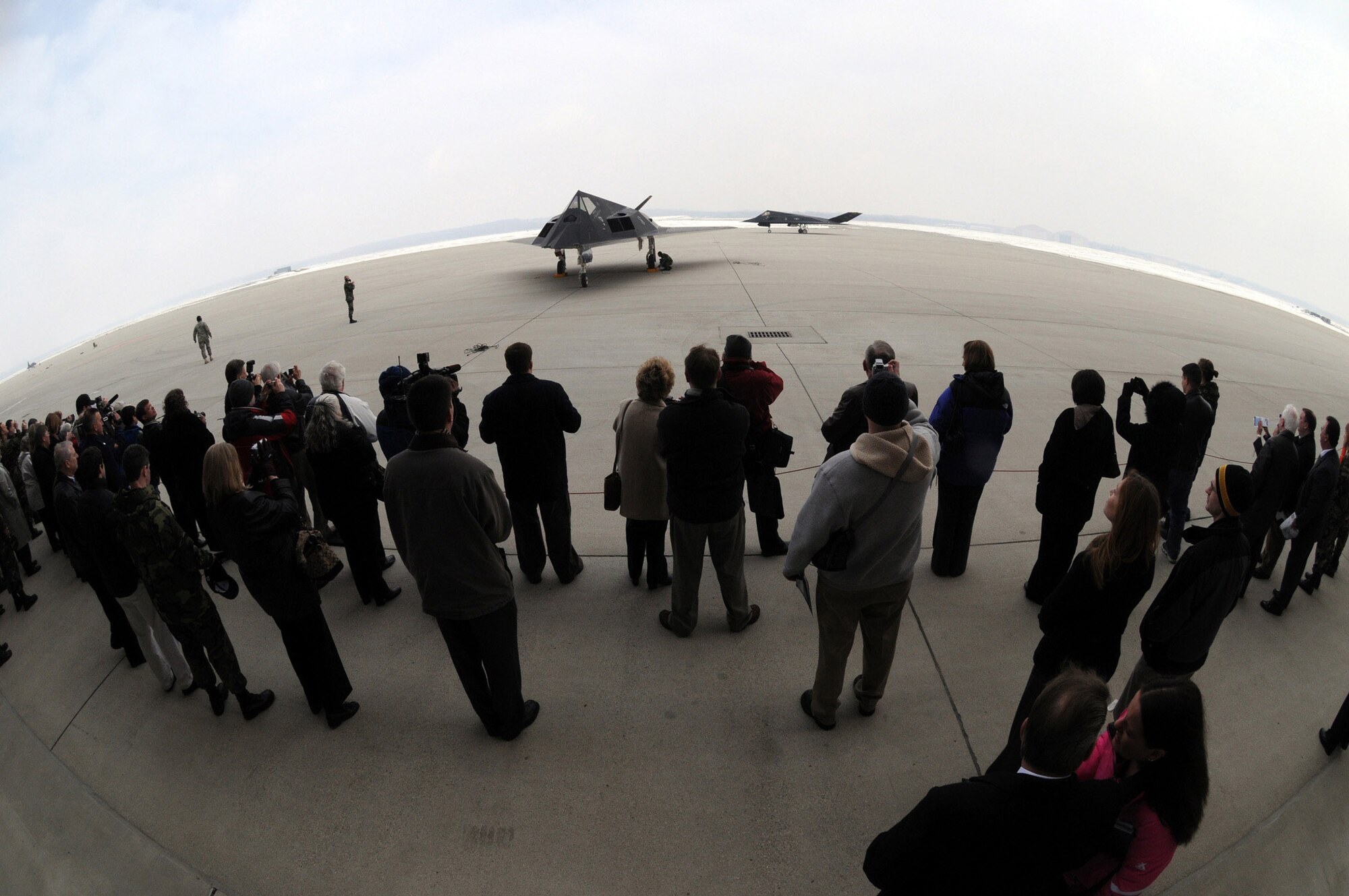 A military and civilian crowd watches as two F-117 Nighthawk aircraft taxi into position during the F-117 Nighthawk farewell ceremony at Wright-Patterson Air Force Base, Ohio, March 11. (U.S. Air Force photo/Staff Sgt Joshua Strang)
