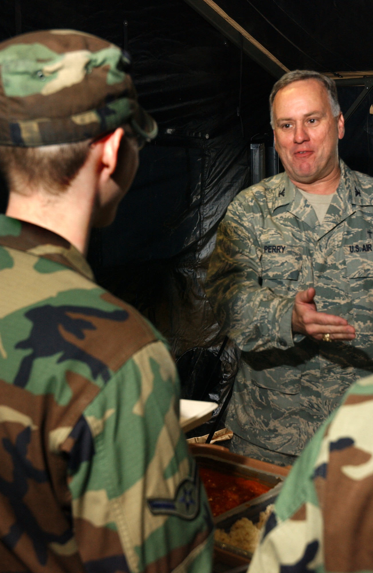 Col. Clifton Perry, 18th Wing chaplain, talks with Airman 1st Class Tye Cavitt, 18th Services Squadron, while choosing from a variety of food offered by the 18th SVS single pallet expeditionary kitchen during the 2008 Pacific Air Forces Operational Readiness Inspection at Kadena Air Base, Japan, March 11, 2008. The deployable kitchen can be set up from pallet to serving in under four hours. PACAF is conducting the inspection from March 9 to 15 to validate the mission readiness of the 18th Wing.  (U.S. Air Force photo/Senior Airman Jeremy McGuffin)