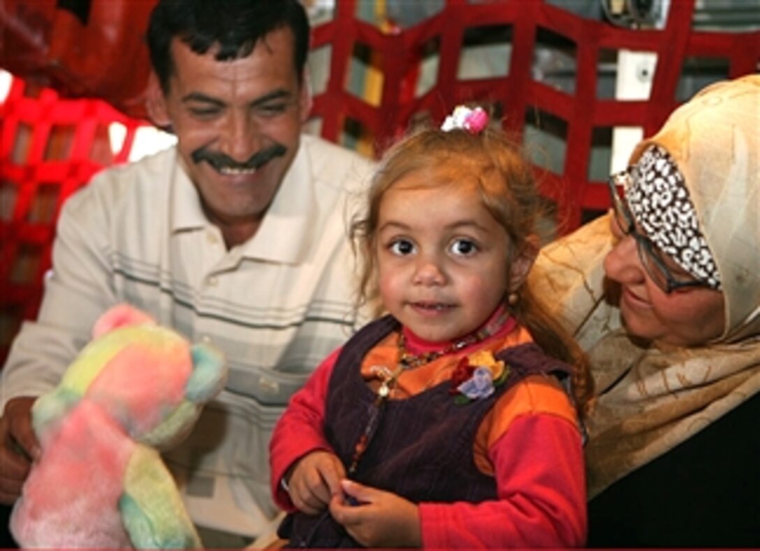 Amenah Thabit, 2, smiles aboard a C-130 Hercules aircraft, March 7, 2008, after she and her mother, Maha Muhamed Bandar, right, returned from the United States where Amenah had heart surgery. Amenah's father, Al'a Thabit Fattah, left, welcomes them home to Haditha, Iraq. A U.S. Marine discovered Amenah on a routine patrol and fellow Marines helped raise money to send her and her mother to the U.S. for treatment.