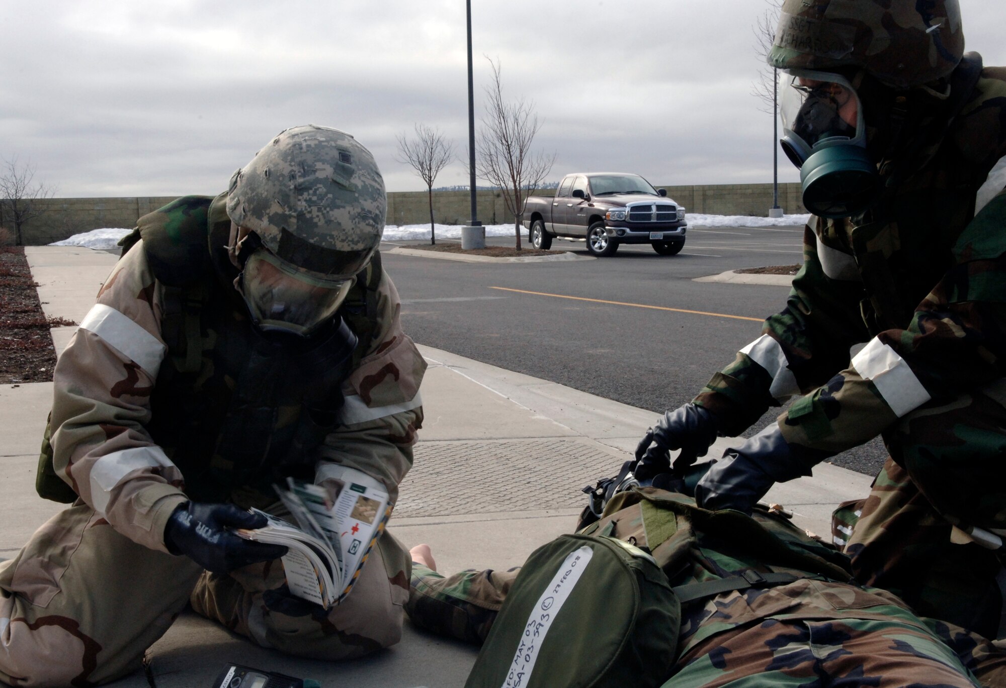 FAIRCHILD AIR FORCE BASE, Wash. – Airman 1st Class Gregory Stoddart and Staff Sgt. Chad Richardson, 92nd Logistics Readiness Squadron, perform Self Aid and Buddy Care to an injured Airman, Staff Sgt. Robert Wetzel, during an exercise March 13. Sergeant Richardson is holding the injured Airman’s gas mask in place while Airman Stoddart is referencing his Airman’s Manual to determine the proper course of action to take in the scenario. The exercise provides Airman with possible real-world scenarios they could face during wartime operations, and gives them the confidence to handle themselves during pressure situations. (U.S. Air Force photo / Airman 1st Class Darlene West) 