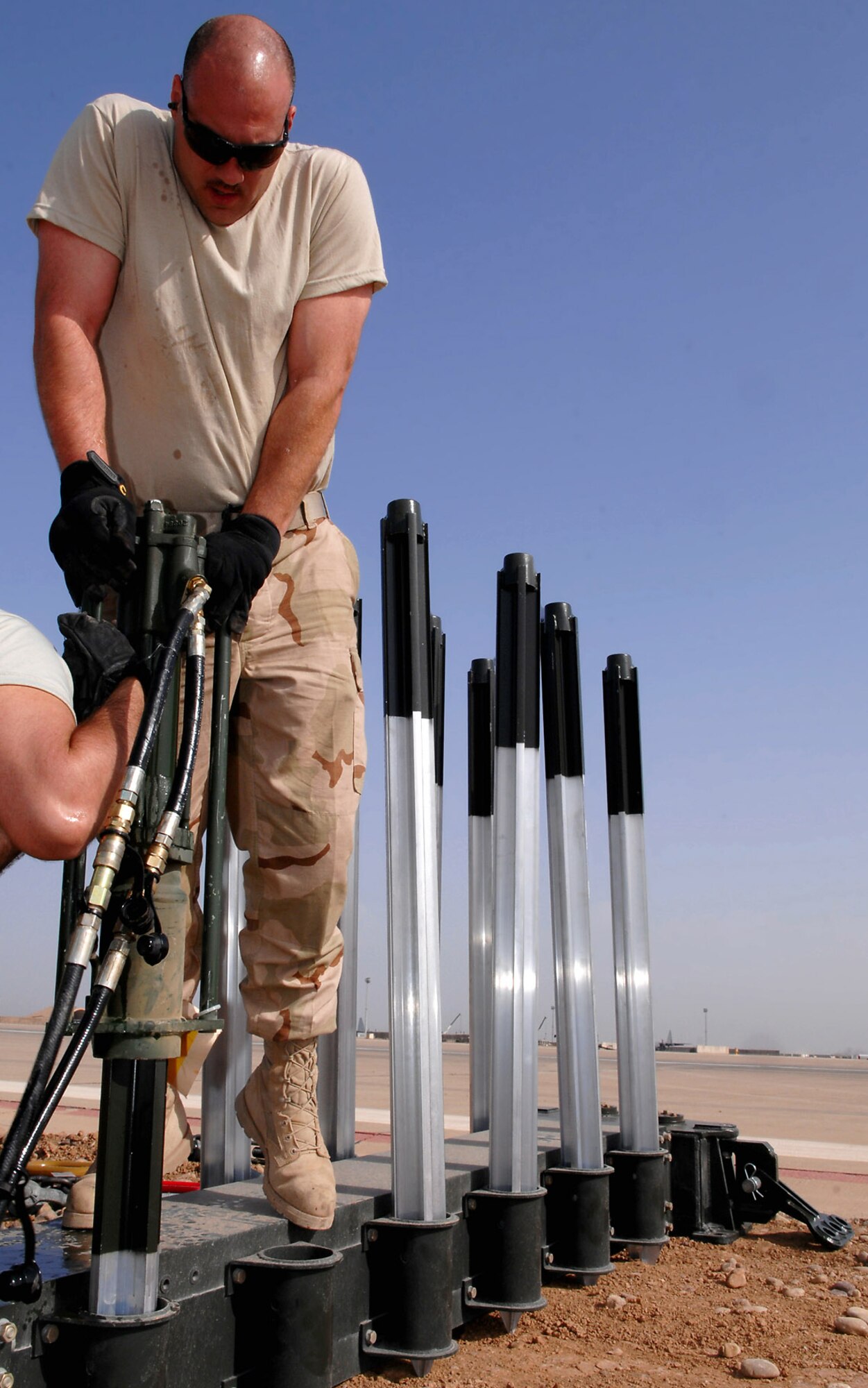Tech. Sgt. Randy Thibeau holds a stake hammer as it pounds a four-foot stake into the ground March 12 at Balad Air Base, Iraq. The stake prevents the arresting barrier system from shifting during an emergency landing. If a fighter aircraft experiences malfunctioning landing gear, the pilot can a drop a hook to catch a cable attached to the barrier system, which slows the aircraft and enables a smoother landing. Sergeant Thibeau is a 332nd Expeditionary Civil Engineer Squadron power production technician deployed from Ellsworth Air Force Base, S.D. (U.S. Air Force photo/Senior Airman Julianne Showalter) 