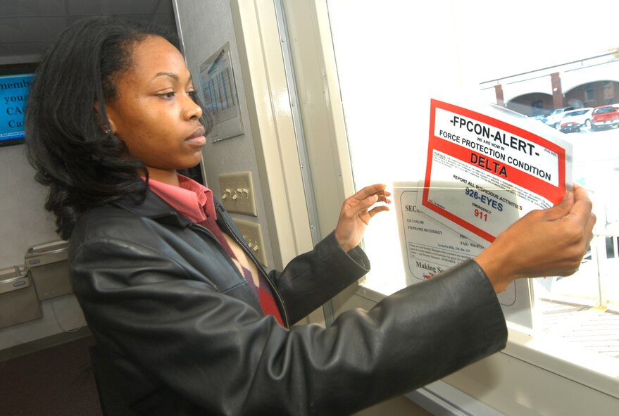 Gevonka Denson posts the Delta force protection condition sign on the door of building 230 modular Tuesday during exercises at Robins. U. S. Air Force photo by Sue Sapp     