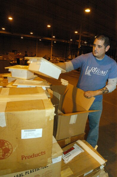Rey Solis, warehouse worker, unpacks boxes of tiems brought in for reutilization. U. S. Air Force photo by Sue Sapp 