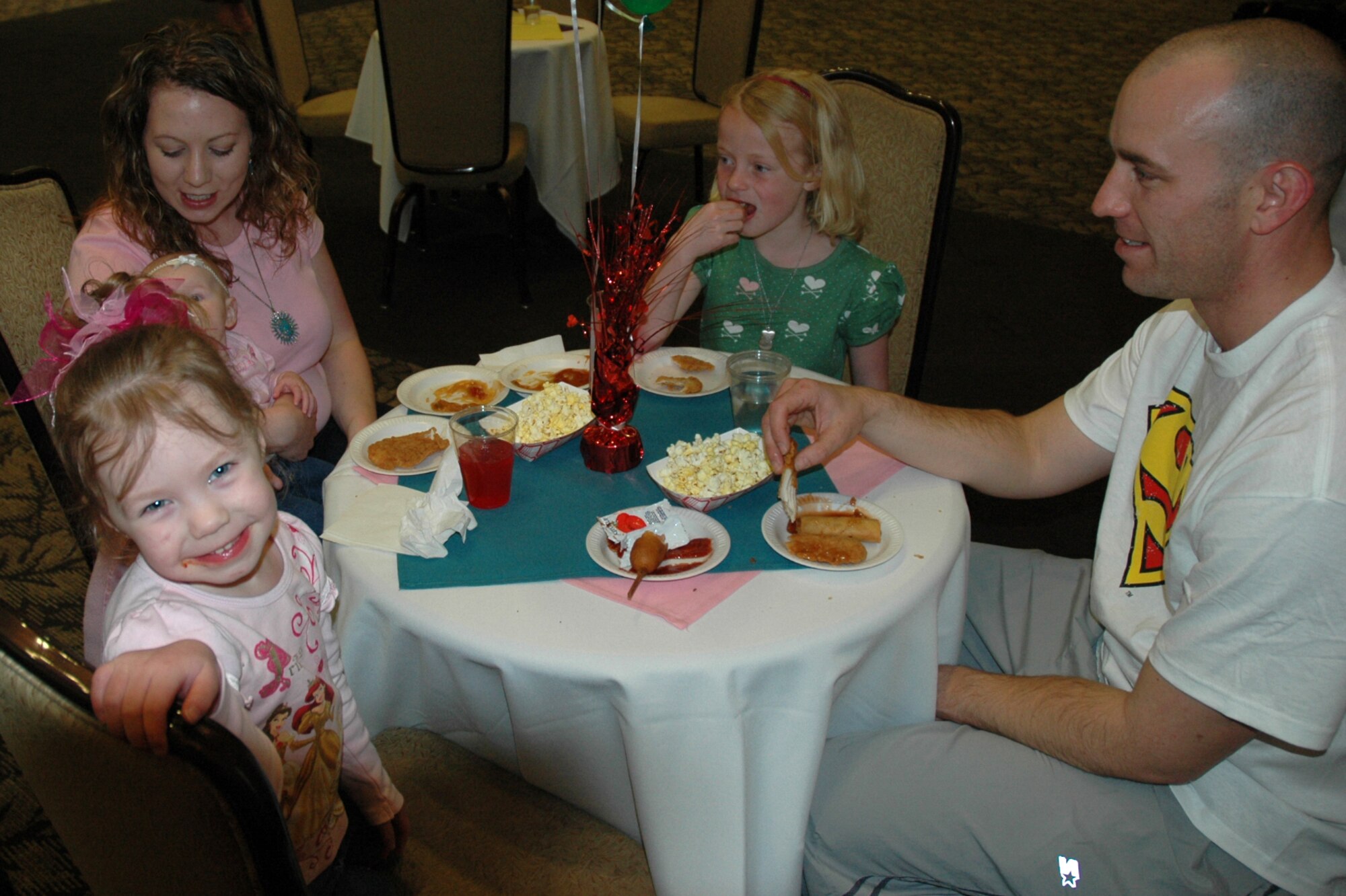 (Left to right) Katie, 3, Terani, 4 months, Tiffany, Raylee, 7, and Staff Sgt. Tim Neal, 388th Equipment Maintenance Squadron, enjoy the food at the Welcome Home Carnival at Club Hill on March 12.