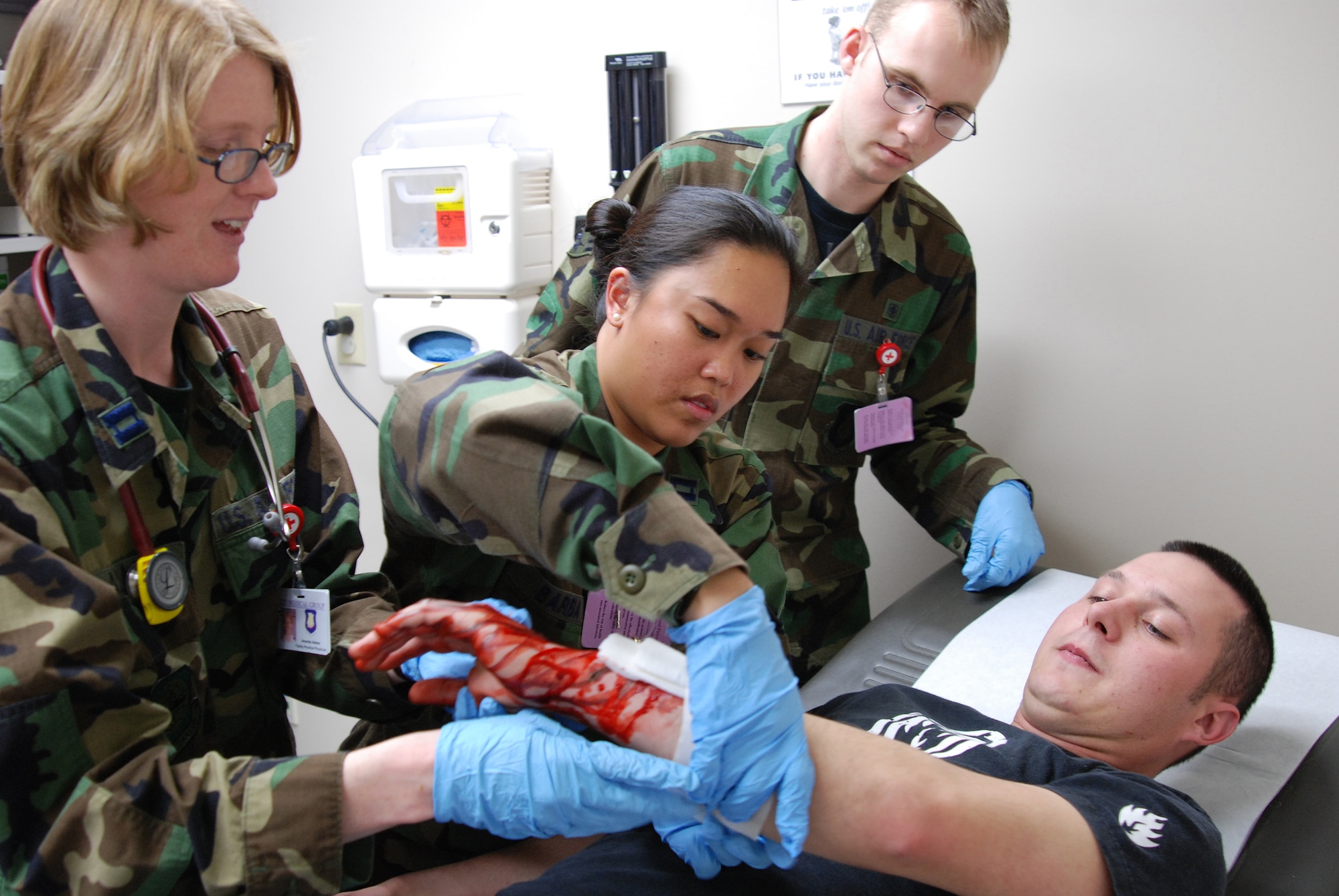 MCCONNELL AIR FORCE BASE, Kan. --22nd Medical Group, Capt. Amanda Adams, Capt. Katrina Barba and Airman 1st Class Paul Bedegi, respond to a simulated arm laceration from Airman 1st Class Abe Helfinstine, 22nd Civil Engineer Squadron, during a base wide tornado response exercise, March 11. (Photo by Airman 1st Class Jessica Lockoski)
