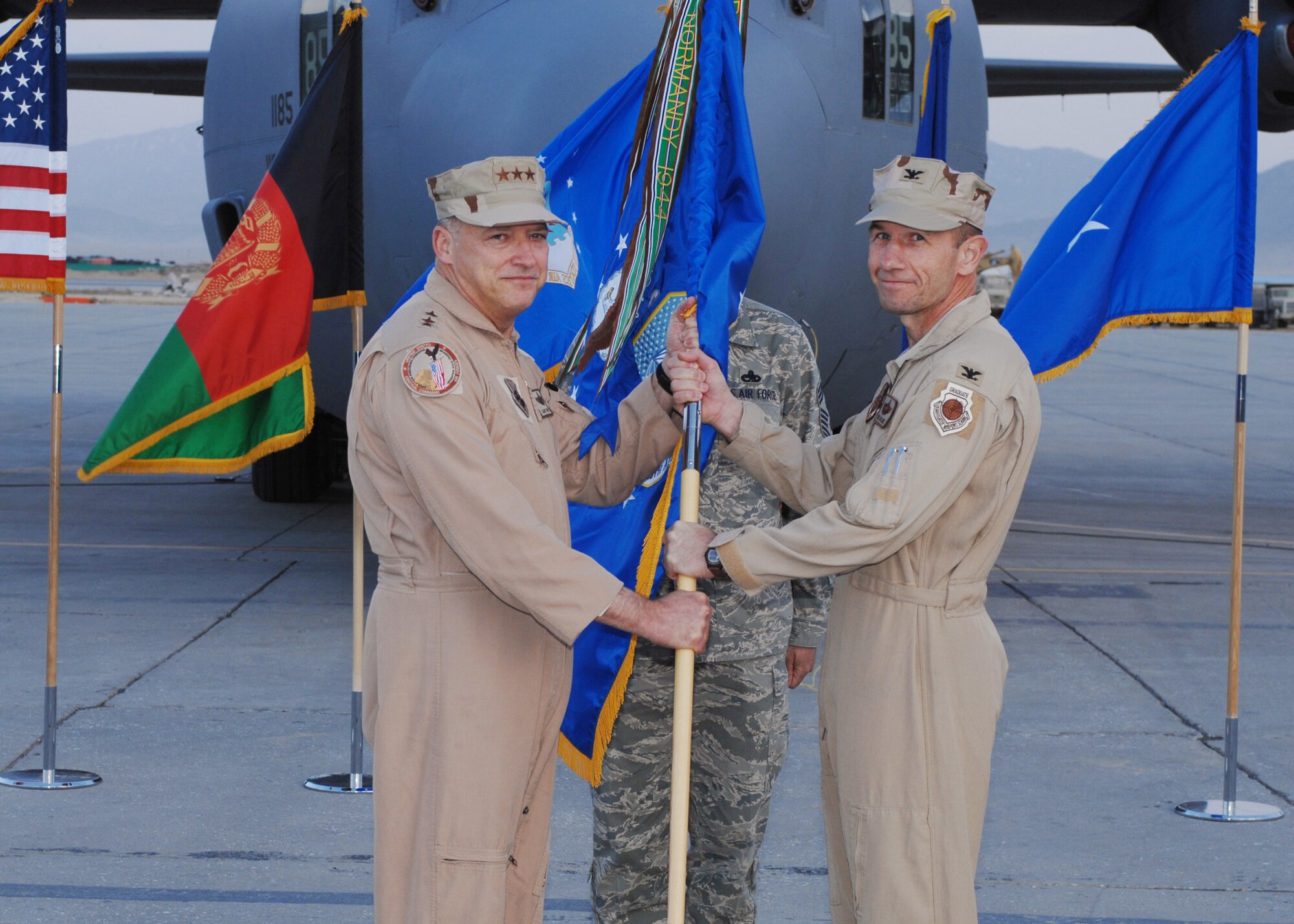 BAGRAM AIR BASE, Afghanistan - Lt. Gen. Gary North, 9th Air Force and U.S. Air Forces Central commander, presents Col. Mike Holmes with the 455th Air Expeditionary Wing guidon making him the wing’s commander here March 10.  Colonel Holmes pinned on brigadier general March 12. (U.S. Air Force photo by Master Sgt. Demetrius Lester)