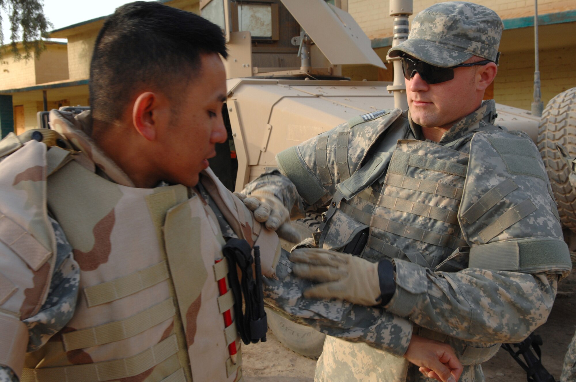 FORWARD OPERATING BASE NORMANDY, Iraq -- Senior Airman Ernesto Racoma (left) and Airman 1st Class Zachary Stratton, utilities technicians assigned to 732nd Expeditionary Civil Engineer Squadron Detachment 6, help each other gear up in preparation for their daily convoy. The Airmen filled Army in-lieu-of taskings, allowing Soldiers to fill Army-specific positions. Both Airmen are deployed from Beale Air Force Base, Calif. (U.S. Air Force photo/ Senior Airman Julianne Showalter)