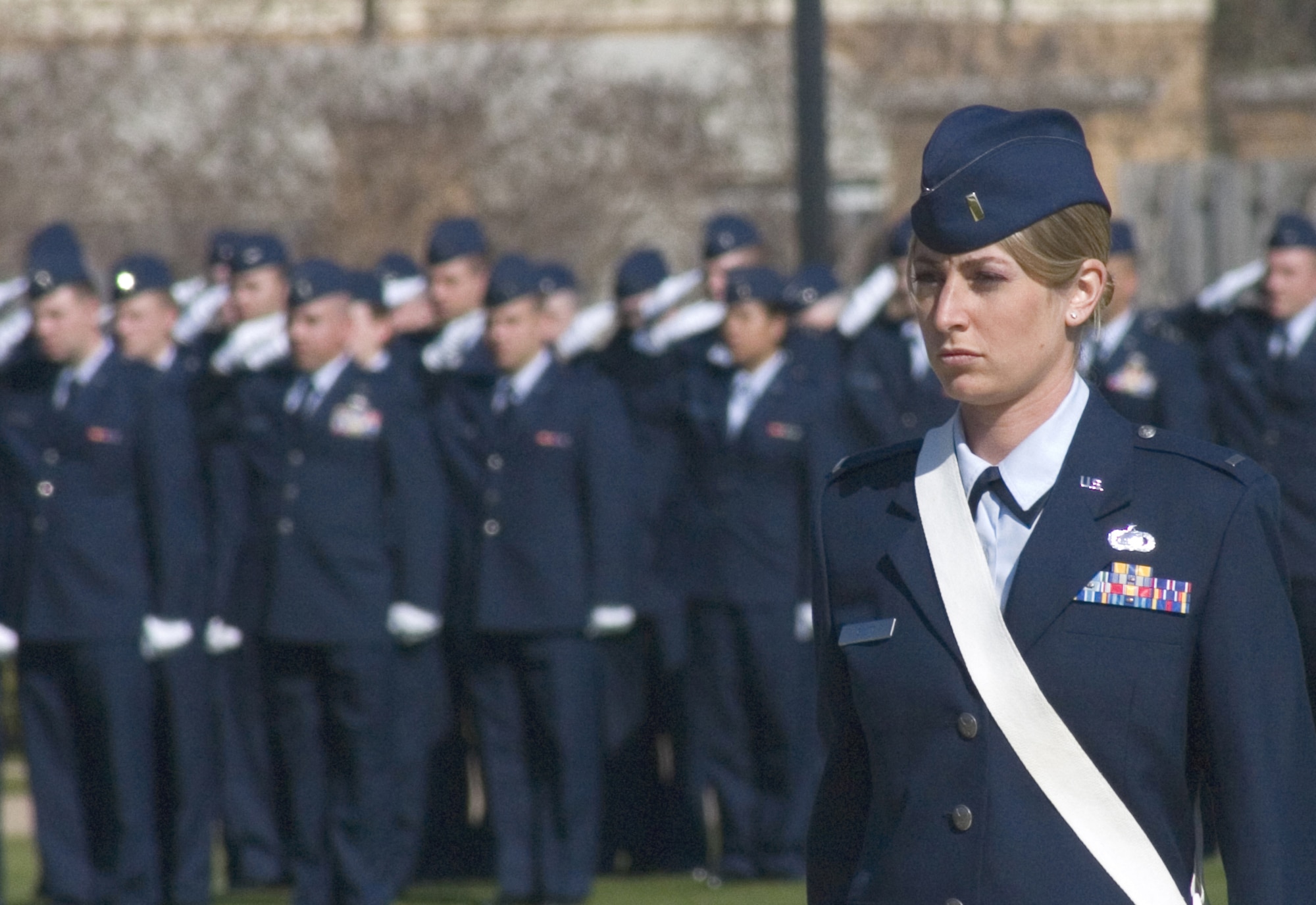 Second lieutenant Kristin Gwitt holds a sabre at the position of attention while basic officer trainees salute during the playing of the National Anthem as part of an Officer Training School graduation parade March 12 at Maxwell AFB, Ala. Sixty-six Airmen completed the 12-week basic officer training course before earning their commission. 