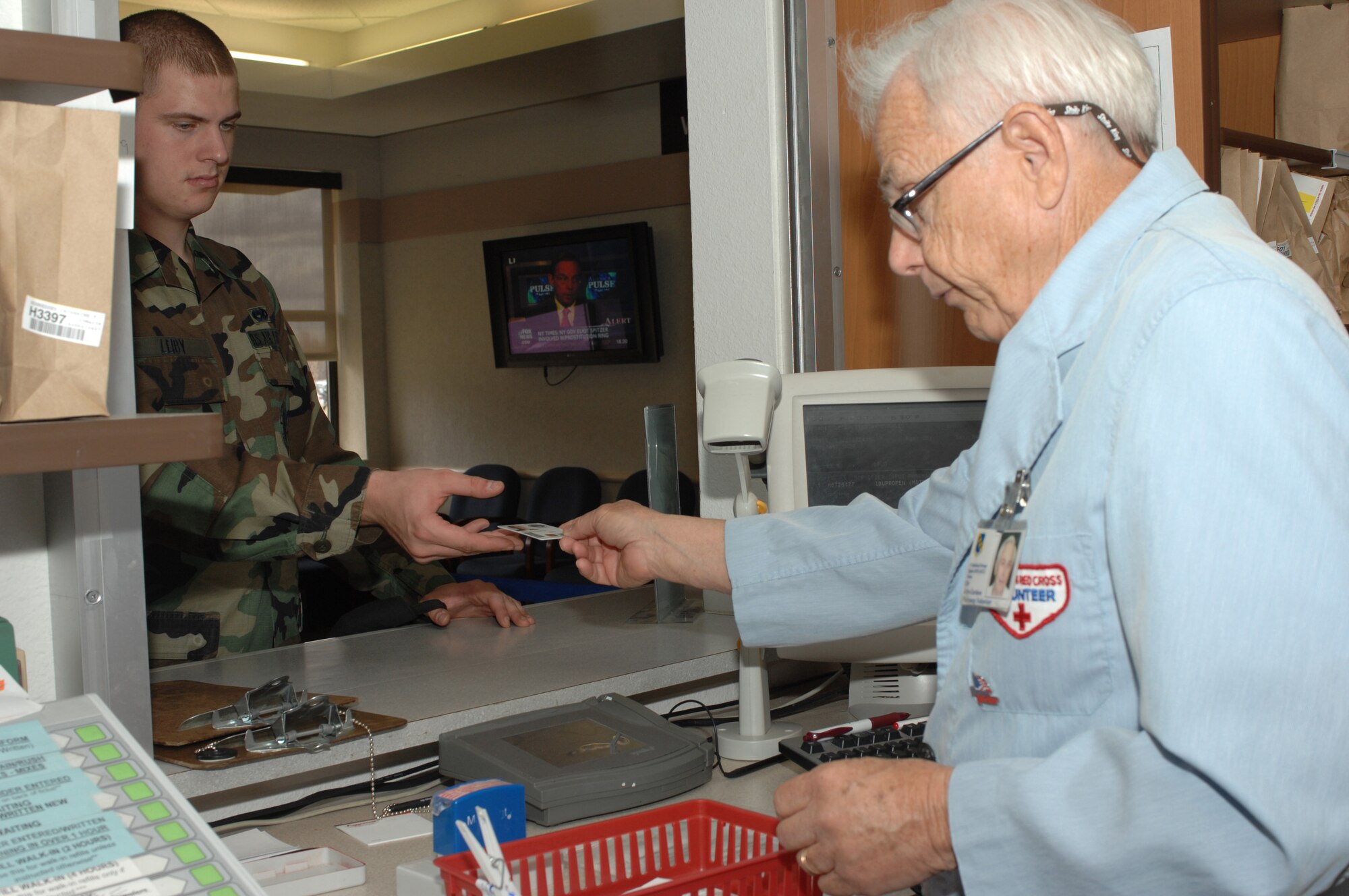 DYESS AIR FORCE BASE, Texas -- John Carlson, volunteer, checks in Airman 1st Class Timothy Leiby, 317th AMXS, at the pharmacy March 10. (U.S. Air Force photo by Senior Airman Courtney Richardson)