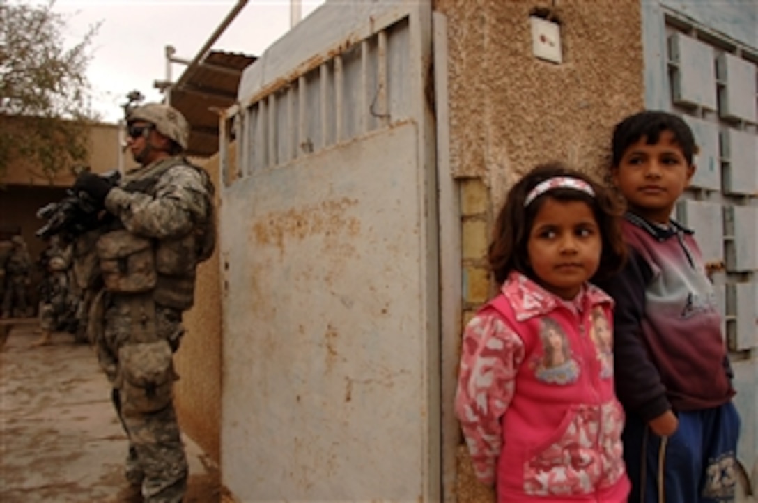 Iraqi children watch as U.S. Army soldiers from Baker Company, 1st Battalion, 15th Infantry Regiment, 3rd Heavy Brigade Combat Team, 3rd Infantry Division visit with local residents to talk about enemy activity during a patrol in a village southeast of Salman Pak, Iraq, on Feb. 15, 2008.  Insurgents have recently occupied the village but the soldiers are working with local residents to improve security.  