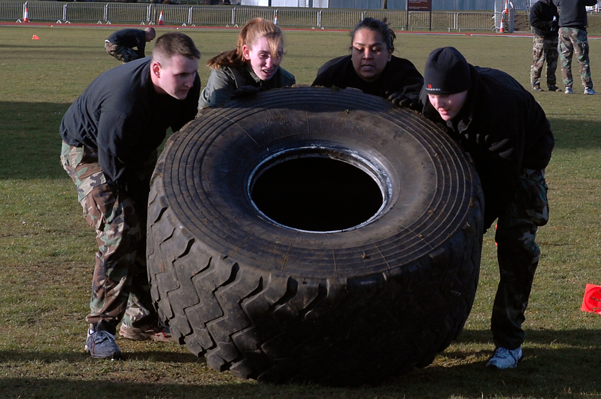 Staff Sgt. Donald Greenwood, Senior Airman Ashley Rea, Staff Sgt. Christina Martinez and Senior Airman Whitney Young, 48th Security Forces Squadron, flip a fire truck tire during the 48th SFS Combat Olympics March 11 at RAF Lakenheath, England. The teams were tasked with flipping two fire truck tires over a course of 30 yards and back. (U.S. Air Force photo by Senior Airman Brian J. Ellis)