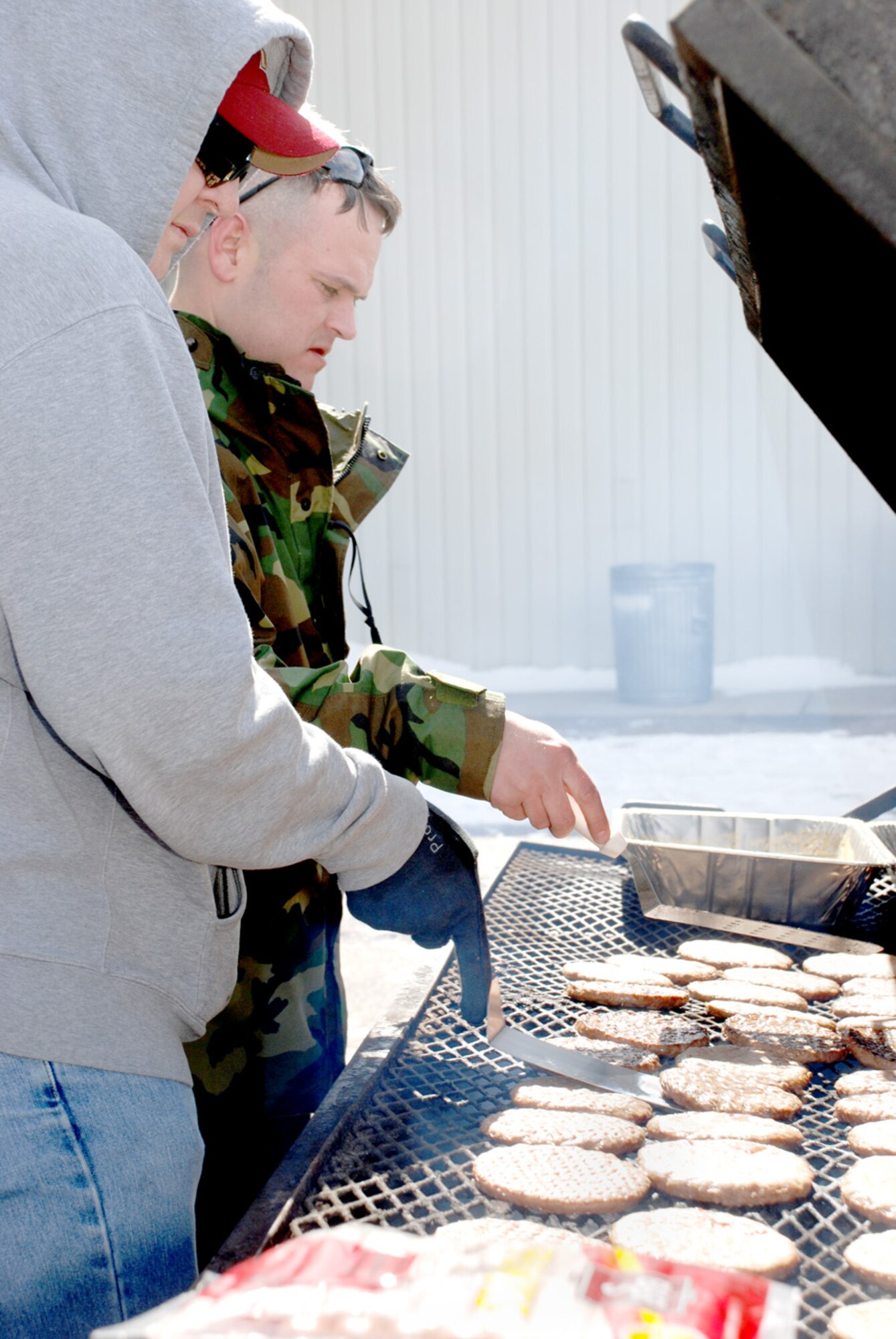 Tech. Sgt. John Krumlauf, 790th Missile Security Forces Squadron, and Tech. Sgt. Troy Grubaugh, 90th Space Wing, grill hamburger patties in Bldg. 1501 for a 90th Security Forces Group barbecue March 7. The occasion was in honor of deploying security forces Airmen (U.S. Air Force photos/Airman 1st Class Alex Martinez).