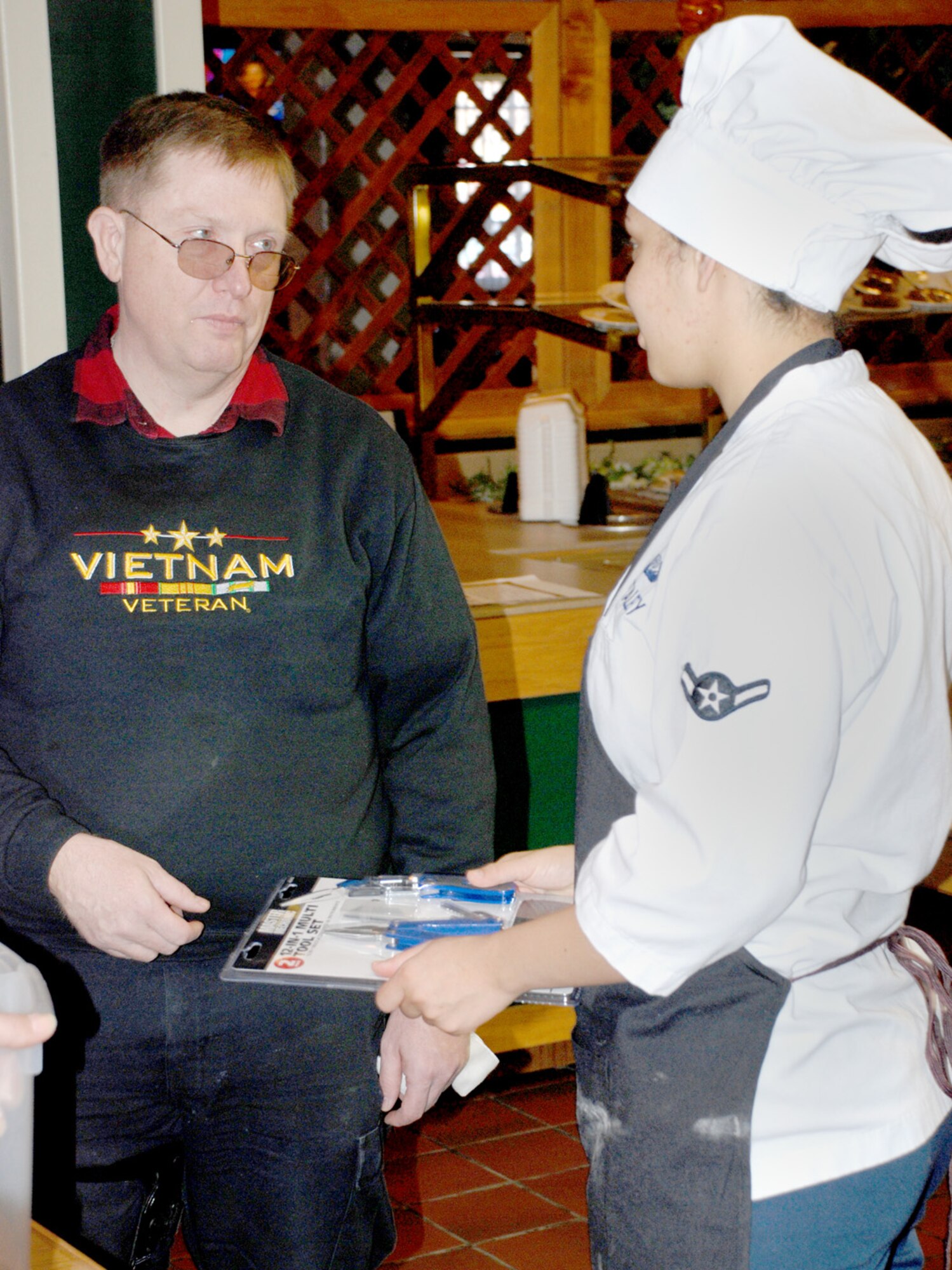 Bruce Jolley, a retired veteran, gives a force support squadron Airman a gift March 4 in the Chadwell Dining Facility. Mr. Jolley and Dennis Mitchell began a cross-country tour in Vancouver, Wash., where they plan to stop and thank troops during their trip (U.S. Air Force photo/Airman 1st Class Daryl Knee).

