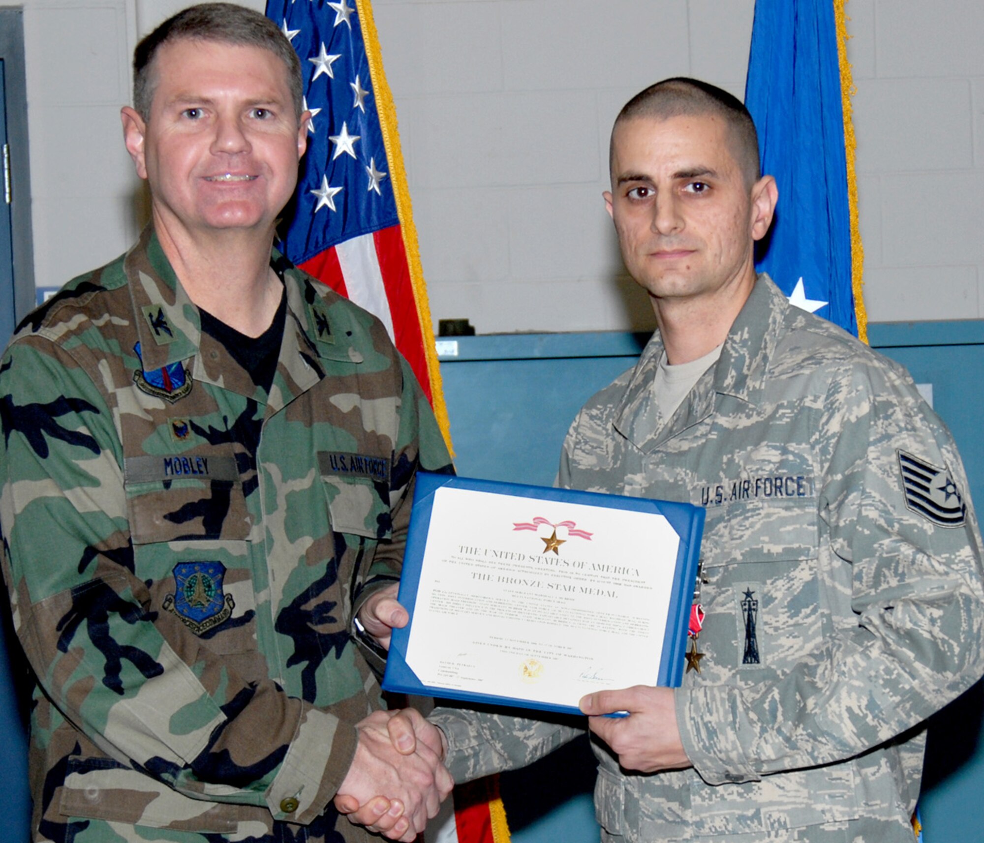 Col. L.B. Mobley, 90th Maintenance Group commander, presents Tech. Sgt. Marshall McBride, former Warren member, a Bronze Star medal for his performance (U.S. Air Force photo).