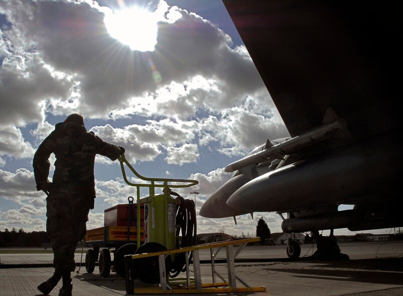 Airman 1st Class David Cooper waits to pull tire chocks as an F-15E Strike Eagle is refueled in the hot pit March 3 at Royal Air Force Lakenheath, England. To minimize ground time, crews regularly perform "hot pits" to allow the aircraft to be refueled while the engines are running. (U.S. Air Force photo/Airman Perry Aston)