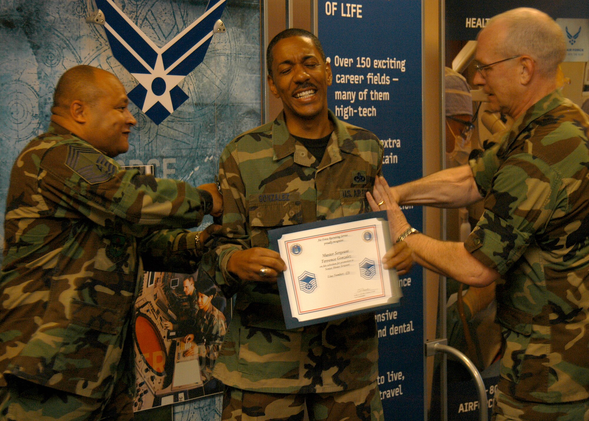 With an equal passion for fun and professionalism, Chief Master Sgt. Edward Vargas (left) tacks promotion stripes on Senior Master Sergeant select Terrence Gonzalez in March 2007 with Col. Stan Chase, Headquarters Air Force Recruiting Service deputy commander at Randolph Air Force Base, Texas. The AFRS Operations Division superintendent retires today, following more than 27 years of active-duty Air Force service. (Staff Sgt. Jennifer Lindsey)