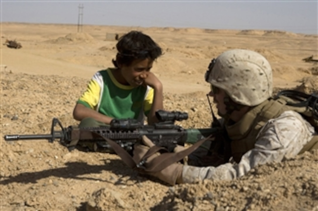 U.S. Marine Corps Lance Cpl. Sean Ward talks with an Iraqi boy while providing security during a patrol in Hit, Iraq, on March 8, 2008.  Ward is from India Company, 3rd Battalion, 4th Marine Regiment, Regimental Combat Team 5.  