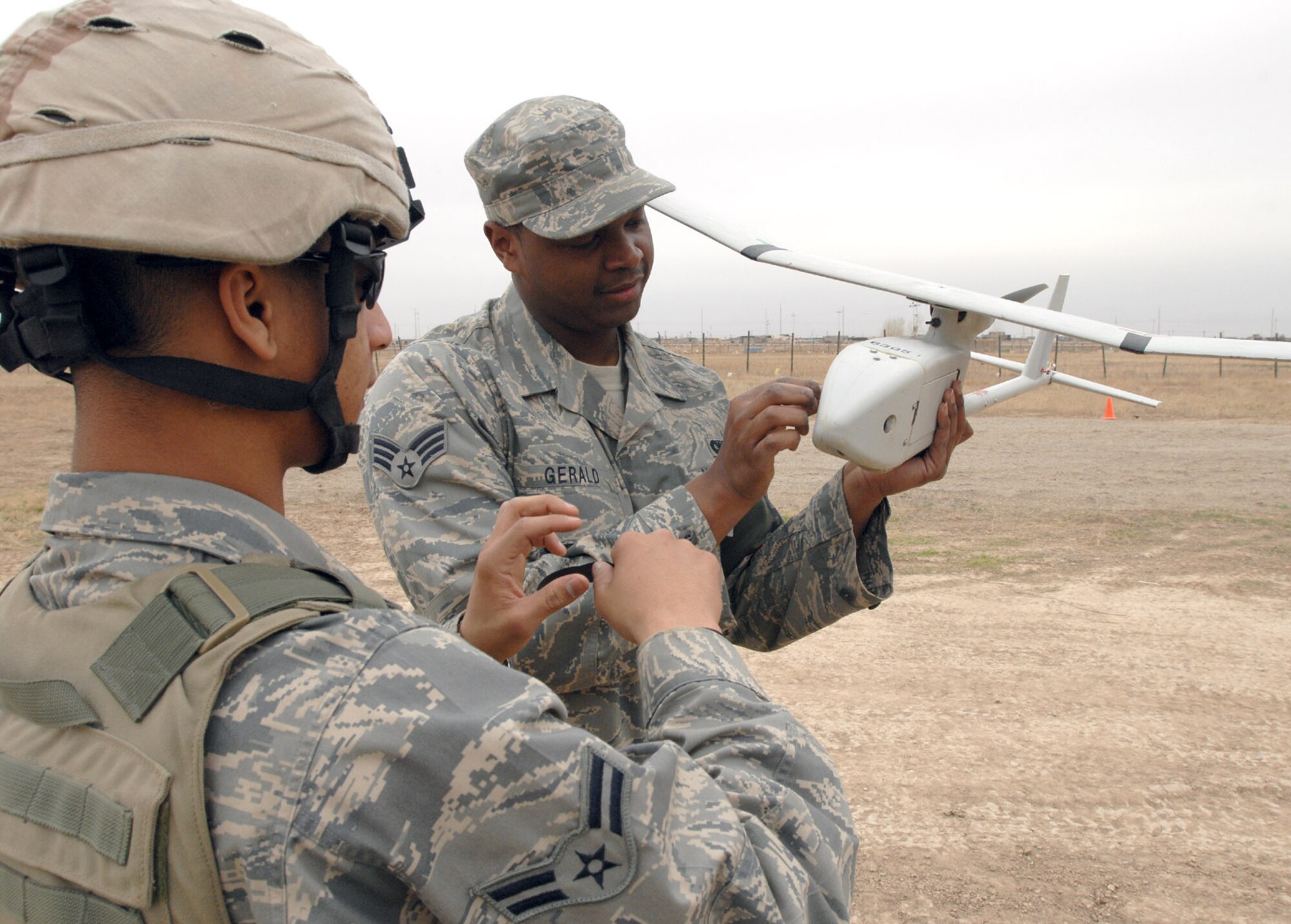 Airman 1st Class Melvin Silva (Right) and Senior Airman Glenn Gerald, 506th Expeditionary Security Forces Squadron Raven operators, perform a pre-flight inspection on an RQ-11 Raven before a recent mission here. Despite weighing in at less than five pounds, this unmanned aerial vehicle plays a vital role in securing the base and surrounding neighborhoods. (U.S. Air Force photo by Senior Master Sgt. Don Senger)