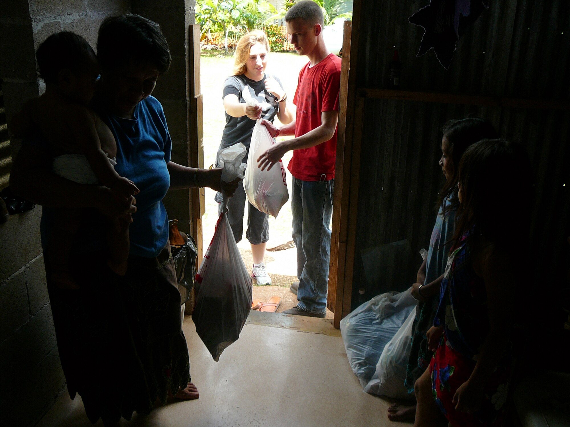 Senior Airmen Michael Uloth, 734th Aircraft Mobility Squadron, and Joan Renfroe, 36th Logistics Readiness Squadron, deliver bags of food and clothing to a local family in Dededo, Guam.  Twenty students from Andersen’s Airman Leadership School Class 08-C volunteered four hours working with The Salvation Army March 15, 2008.  More than 100 bags of clothes and food donated by the Andersen community were bagged and personally delivered to 25 homes consisting of 99 adults and 87 children in Dededo, Guam.  For information on how to donate items to the Guam community through The Salvation Army, call 647-1569.  