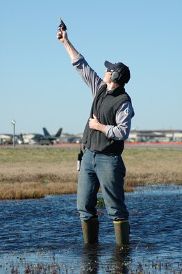 LANGLEY AIR FORCE BASE, Va. -- U.S. Department of Agriculture Wildlife Biologist Tom Olexa, shoots pyrotechnics in front of the runway here to disperse a flock of birds before a pair of F-22 Raptors (background) take off. Wet areas around the runway attract all sorts of wildlife, including birds, which pose a hazard to launching aircraft. Mr. Olexa works with the 1st Fighter Wing's Bird and Wildlife Aircraft Strike Hazard team, known as BASH.