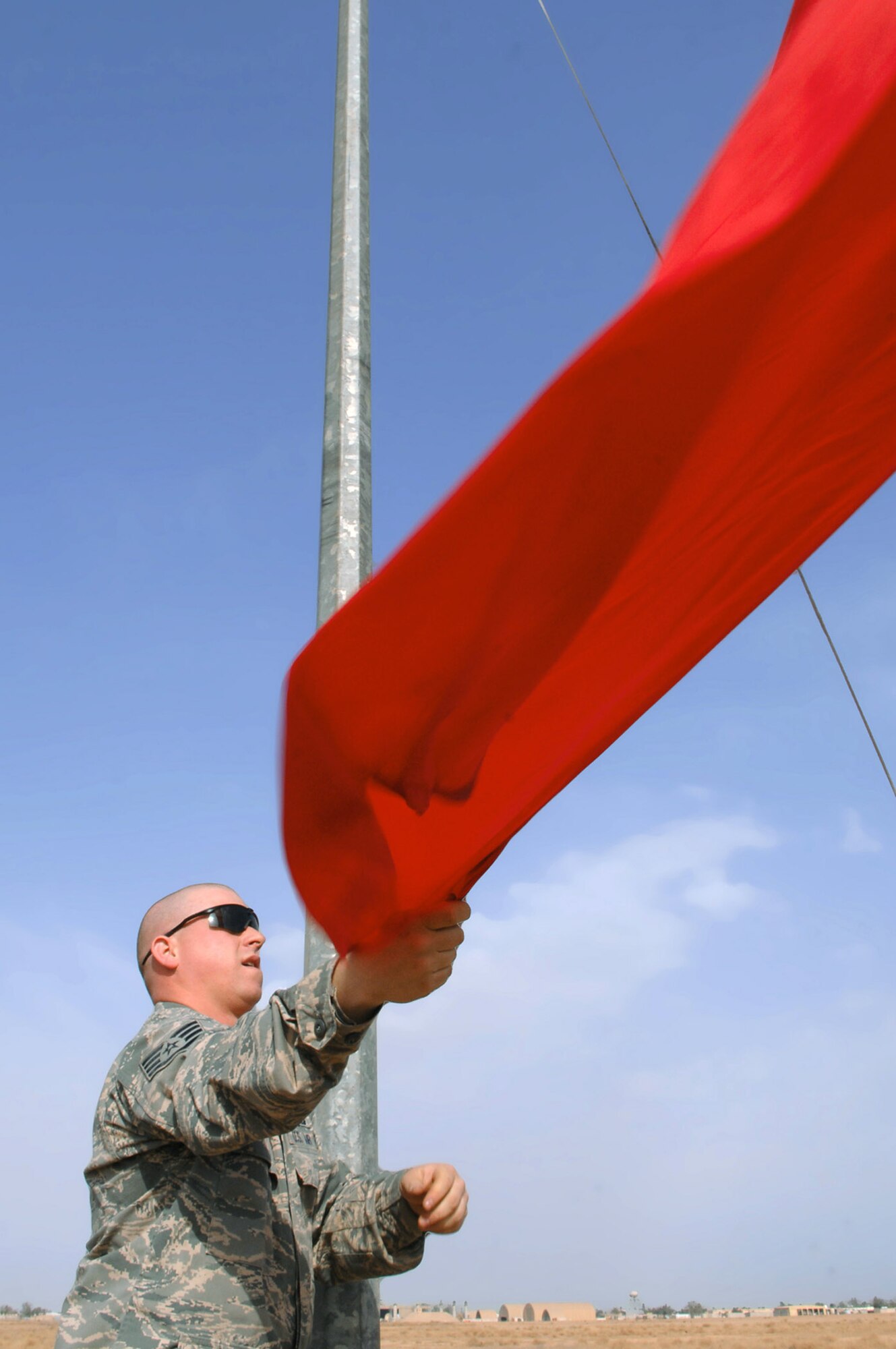 Staff Sgt. Jason Kreider raises a red flag March 13 at Balad Air Base, Iraq. The flag signifies that the ordnance range has become active and that personnel should keep out. Sergeant Kreider is a 332nd Expeditionary Civil Engineer Squadron explosive ordnance disposal technician deployed from Fort Dix, N.J. (U.S. Air Force photo/Senior Airman Julianne Showalter) 