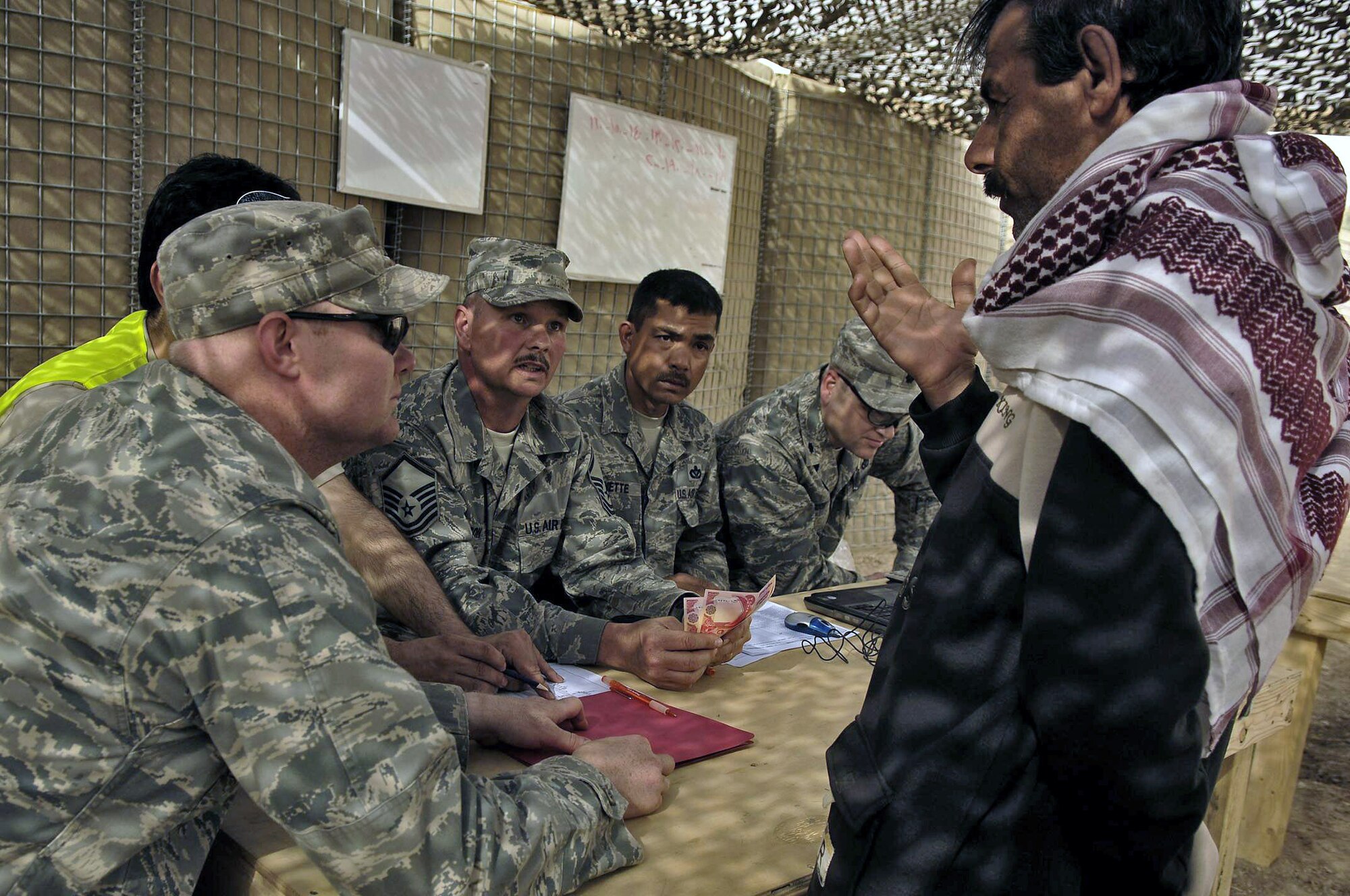 Master Sgt. John Hudson and members of the 557th Expeditionary Red Horse Squadron, headquartered at Balad Air Base, Iraq, pay out nearly $10,000 to 120 students March 13 at the Red Horse Village of Hope school in Hawr Rajab, Iraq. Similar to a technical school, Iraqi students are taught rebuilding skills such as masonry, electrical and plumbing. Sergeant Hudson, an Air Force Reserve Command logistics technician who worked in an accounting department in the civilian sector for 11 years, oversaw the payday. (U.S. Air Force photo)

