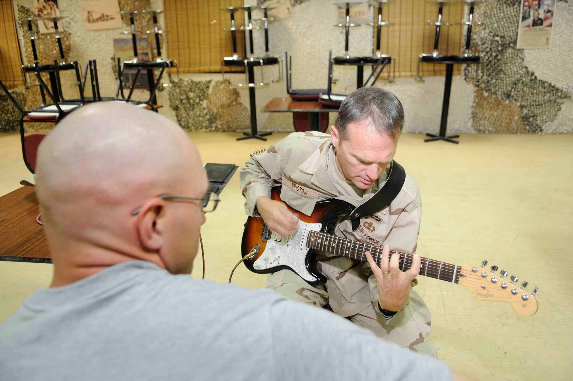 Senior Master Sgt. James Bristow helps 1st Lt. Steven Kline, Alpha 2-43 Air Missile Defense unit, build his guitar chord vocabulary at a Southwest Asia air base March 16. Sergeant Bristow a guitarist and vocalist for the Air Forces Central Band Live Round, performs for service men and women and local communities throughout Southwest Asia.   He is from Manhattan, Kan. deployed from the United States Air Force Academy, Colo. (U.S. Air Force photo/Tech. Sgt. Johnny L. Saldivar)
