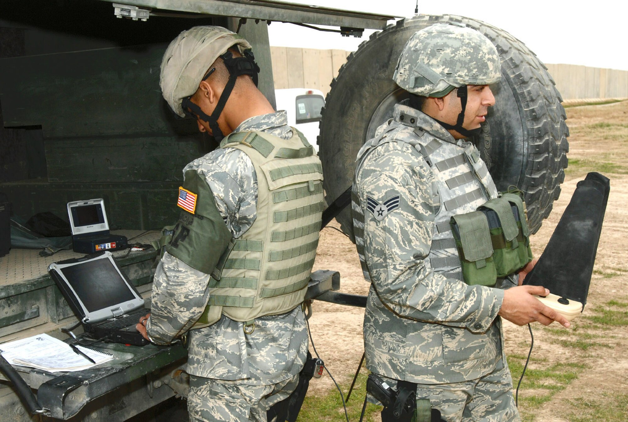 Airman 1st Class Melvin Silva (left) and Senior Airman Jacob Galindo, 506th Expeditionary Security Forces Squadron Raven operators, work together to view images transmitted from an RQ-11 Raven during a recent mission here. Despite weighing in at less than five pounds, this unmanned aerial vehicle plays a vital role in securing the base and surrounding neighborhoods. Airmen Silva and Galindo are 506th Expeditionary Security Forces Squadron Raven operators. (U.S. Air Force photo/Senior Master Sgt. Don Senger) 
