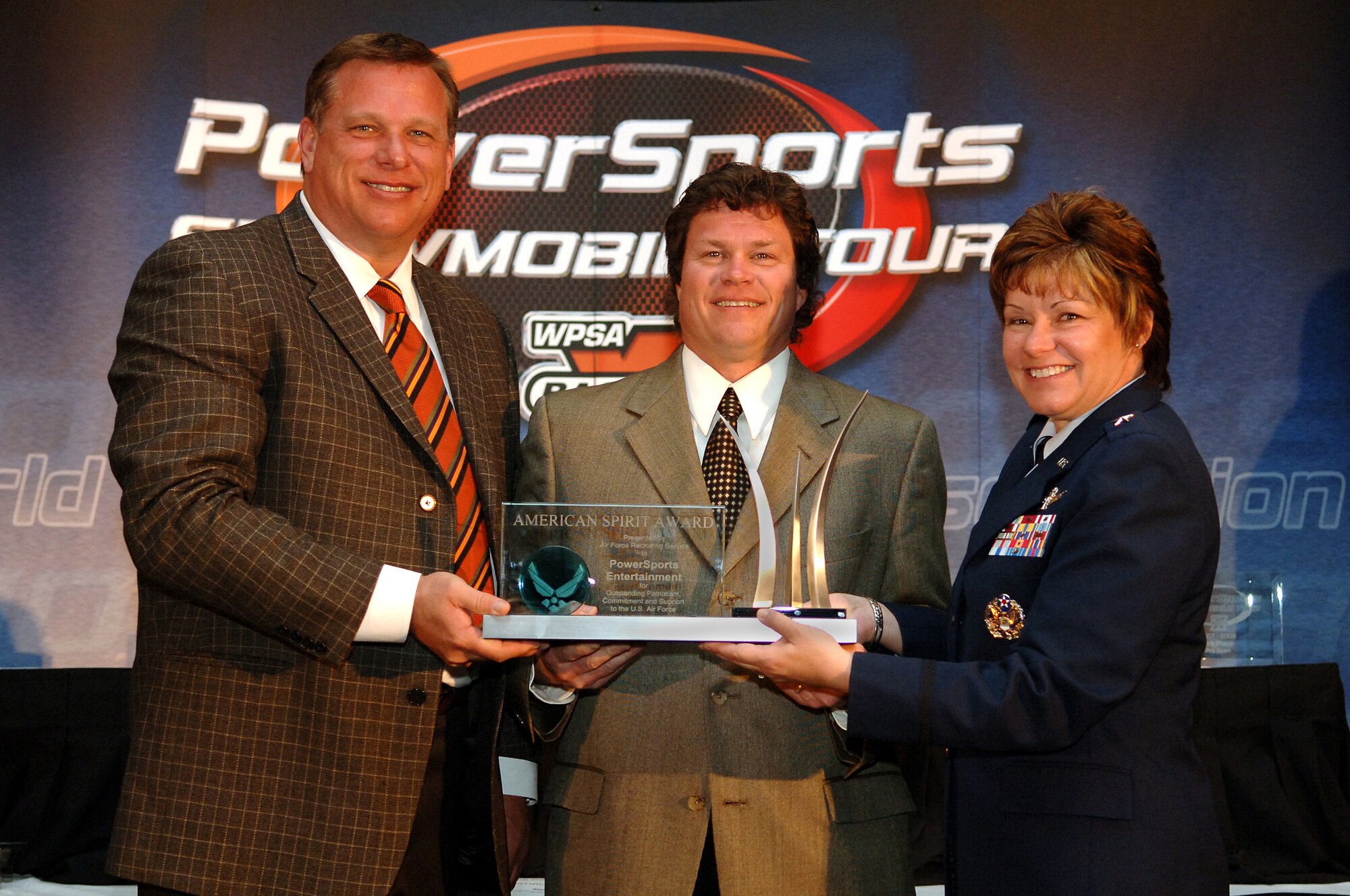 Brig. Gen. Suzanne M. Vautrinot, Air Force Recruiting Service commander, presents the American Spirit Award to Scott O'Malley, center, PowerSports Entertainment Inc. president and Rick Murphy, left, the corporation’s chief executive officer, at the World PowerSports Association Snowmobile Tour National Awards Banquet in Lake Geneva, Wis., March 16. The American Spirit Award is the Air Force's highest form of civilian recognition for support to the Air Force. PowerSports Entertainment Inc. has supported Air Force recruiting efforts for the past ten years. (U.S. Air Force photo/Master Sgt. Scott Reed)