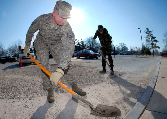 Tech. Sgt. Klinton Bruck, 375th Civil Engineer Squadron utilities systems journeyman, and Airman 1st Class Arla Hooser, 375th CES utilities systems apprentice, help clean up Scott Air Force Base by clearing gravel from the Scott Inn parking lot March 10.

Photo by Airman 1st Class Megan Gilliland